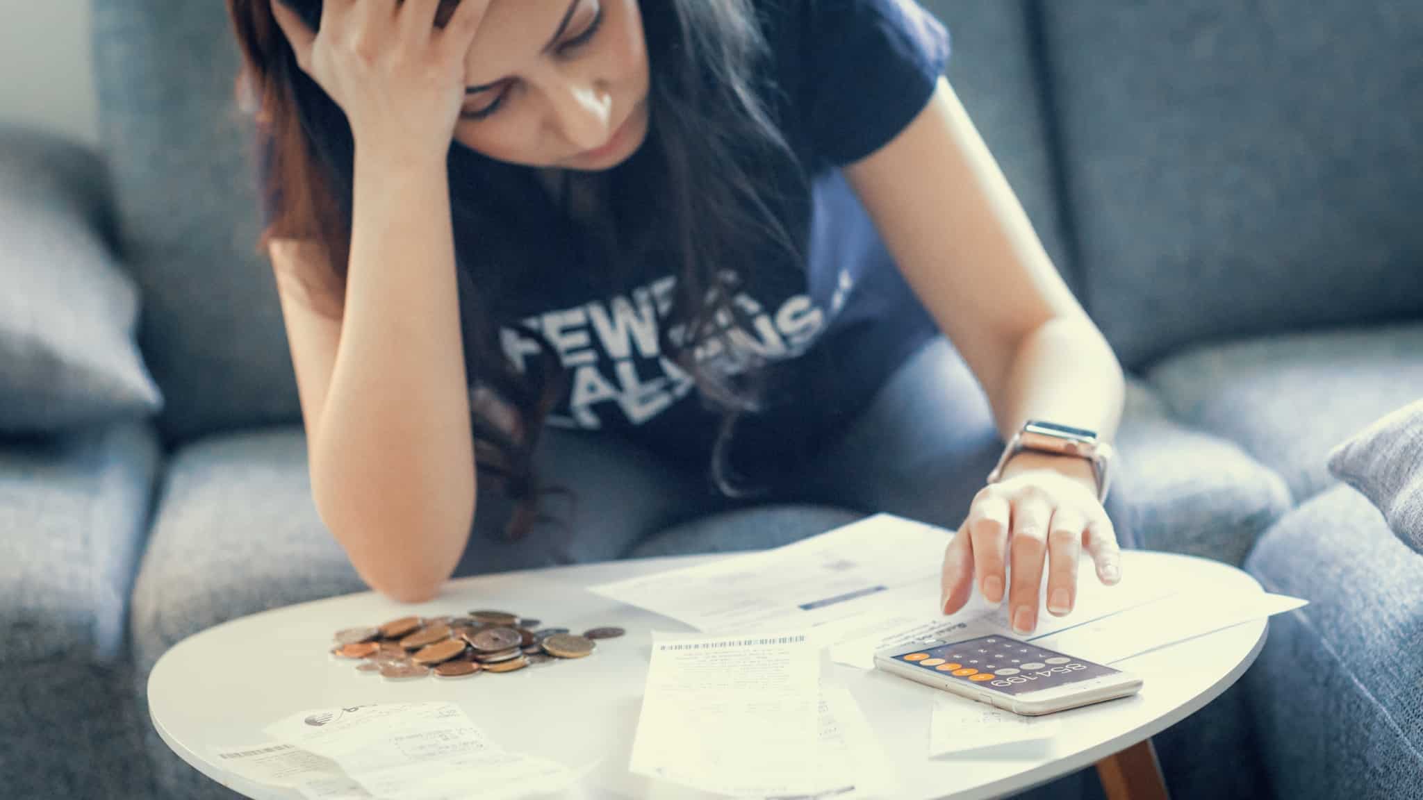 mulher com expressão triste a fazer contas