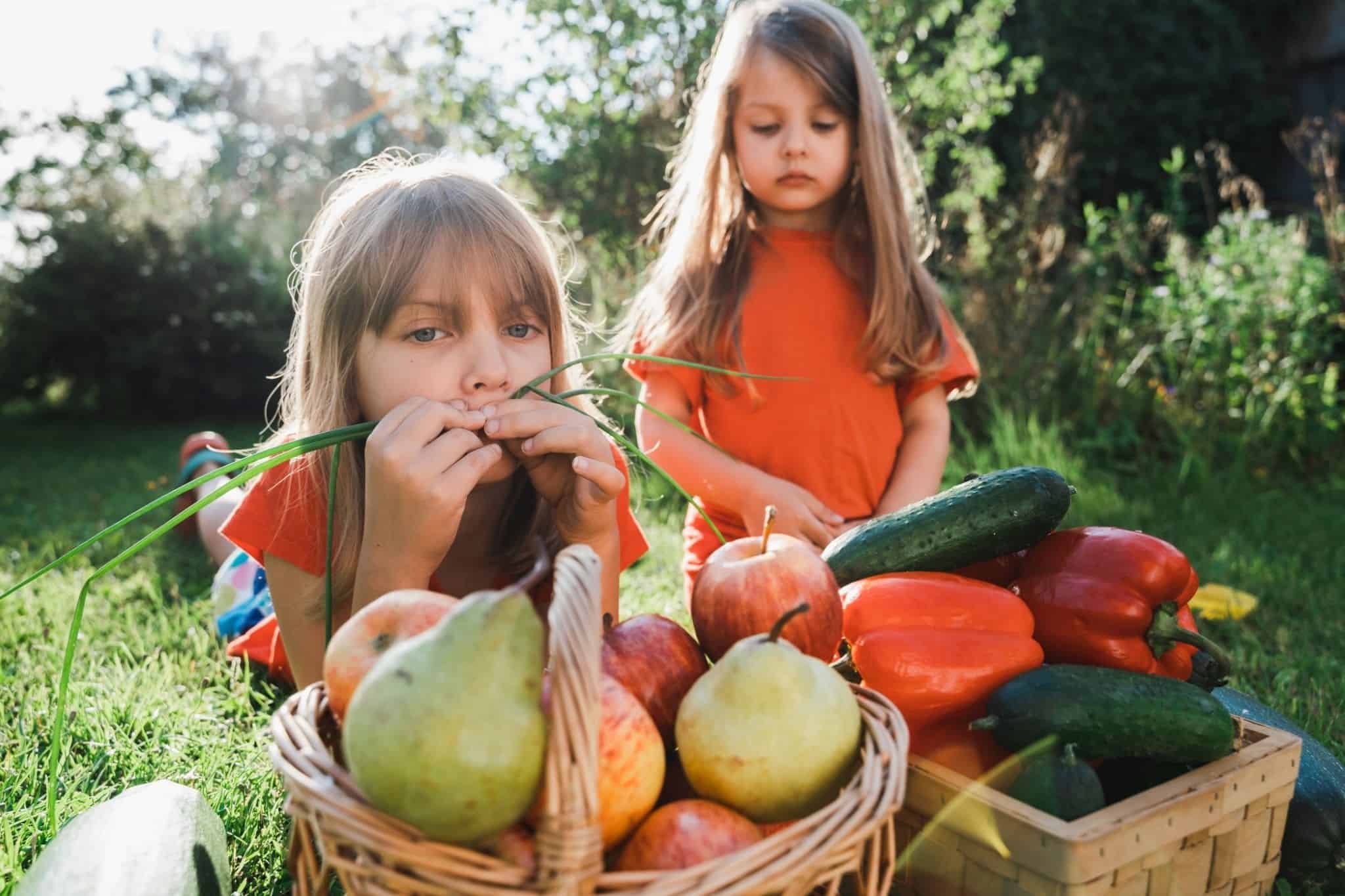 Crianças em frente a cabazes de fruta e legumes a evocar o despedício alimentar