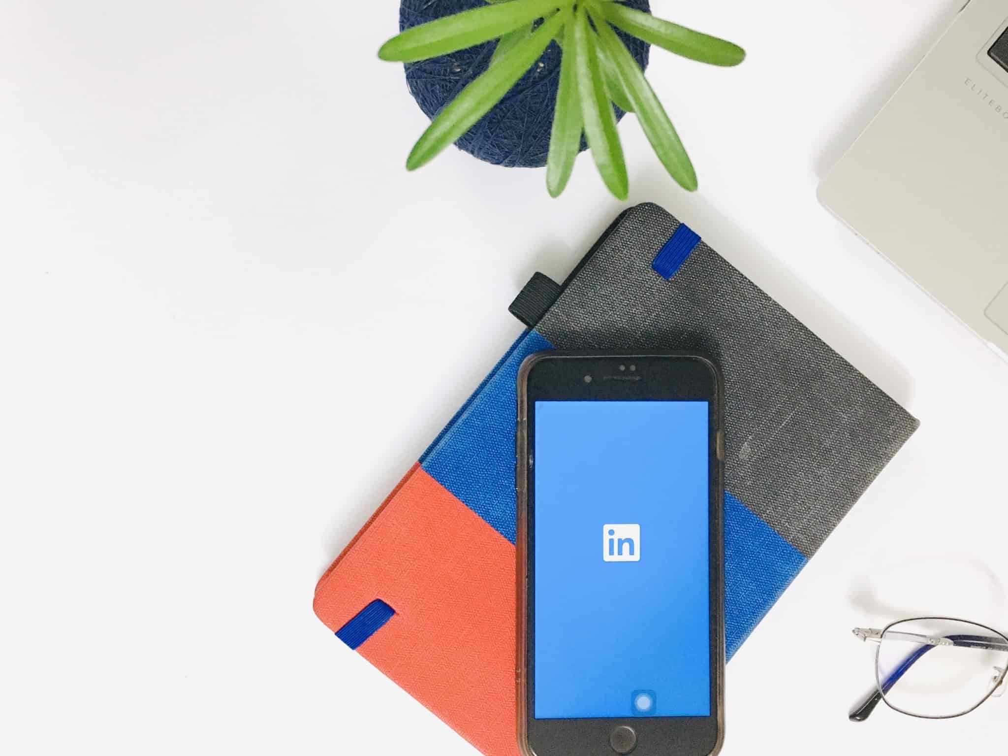 Telemóvel, pousado sobre caderno de apontamentos, mostra no ecran o logótipo do LinkedIn, rede social profissional
