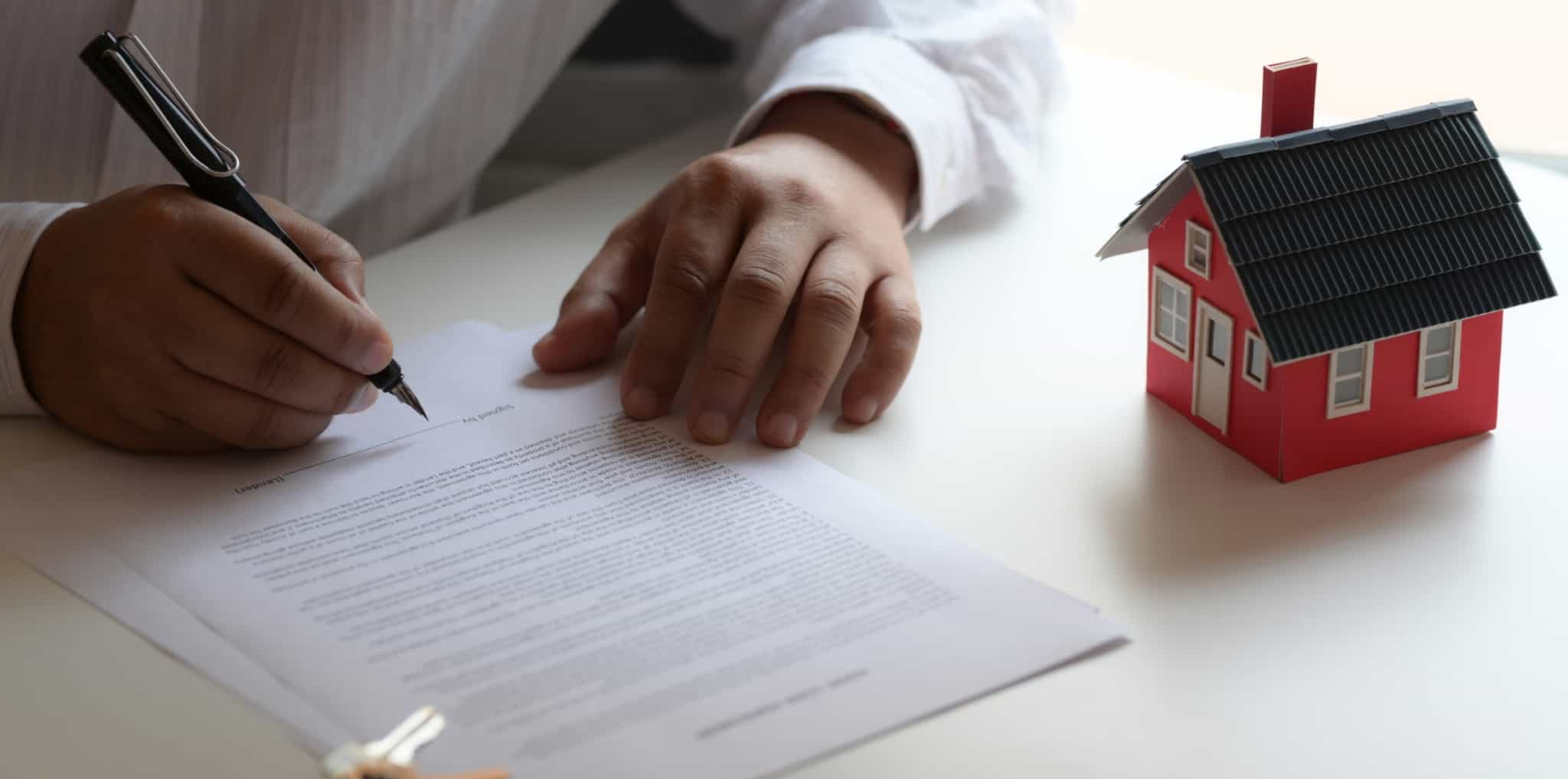 Homem a assinar um contrato para comprar casa, analisando as dívidas ao condomínio