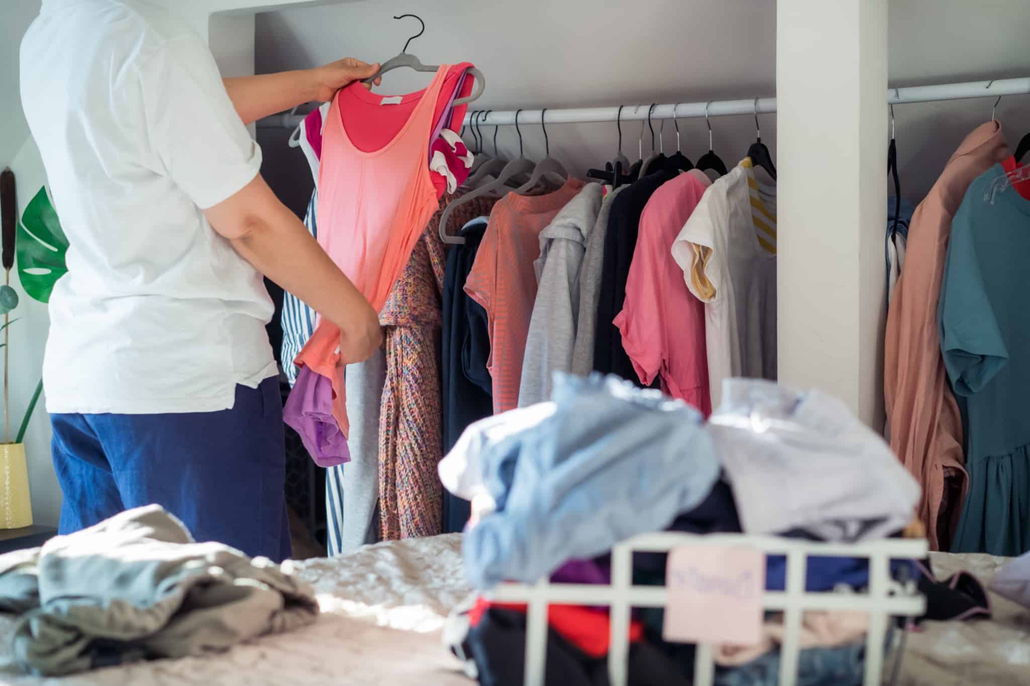 Jovem mulher faz uma triagem às suas roupas para criar um guarda roupa sustentável