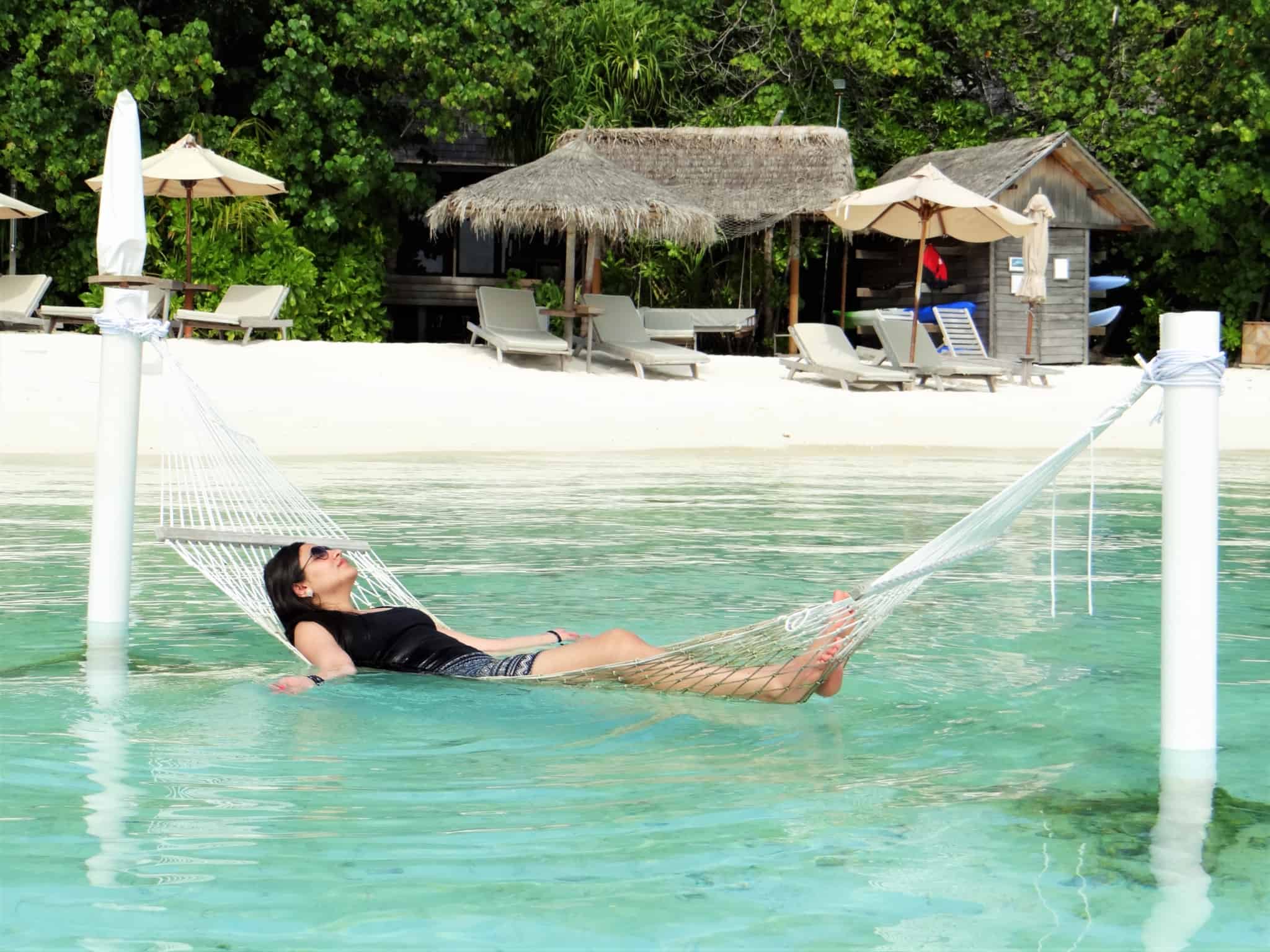 A importância de desligar do trabalho em férias. Jovem mulher relaxa em cama de rede num destino paradisiaco