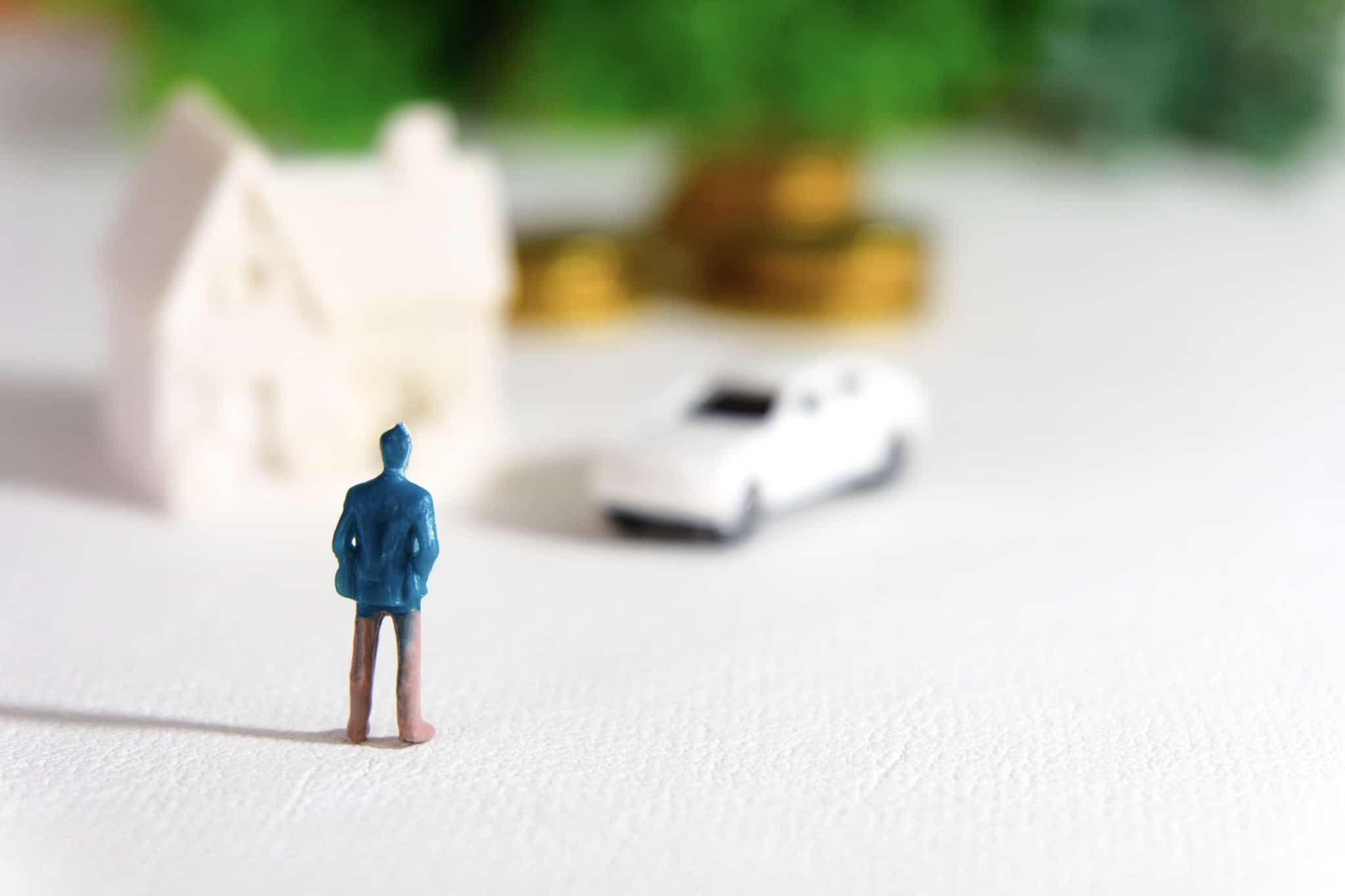 Como ficar rico. Uma produção fotrográfica com um boneco que liustra um jovem homem a sonhar com bens materiais, desfocados no pano de fundo da imagem.