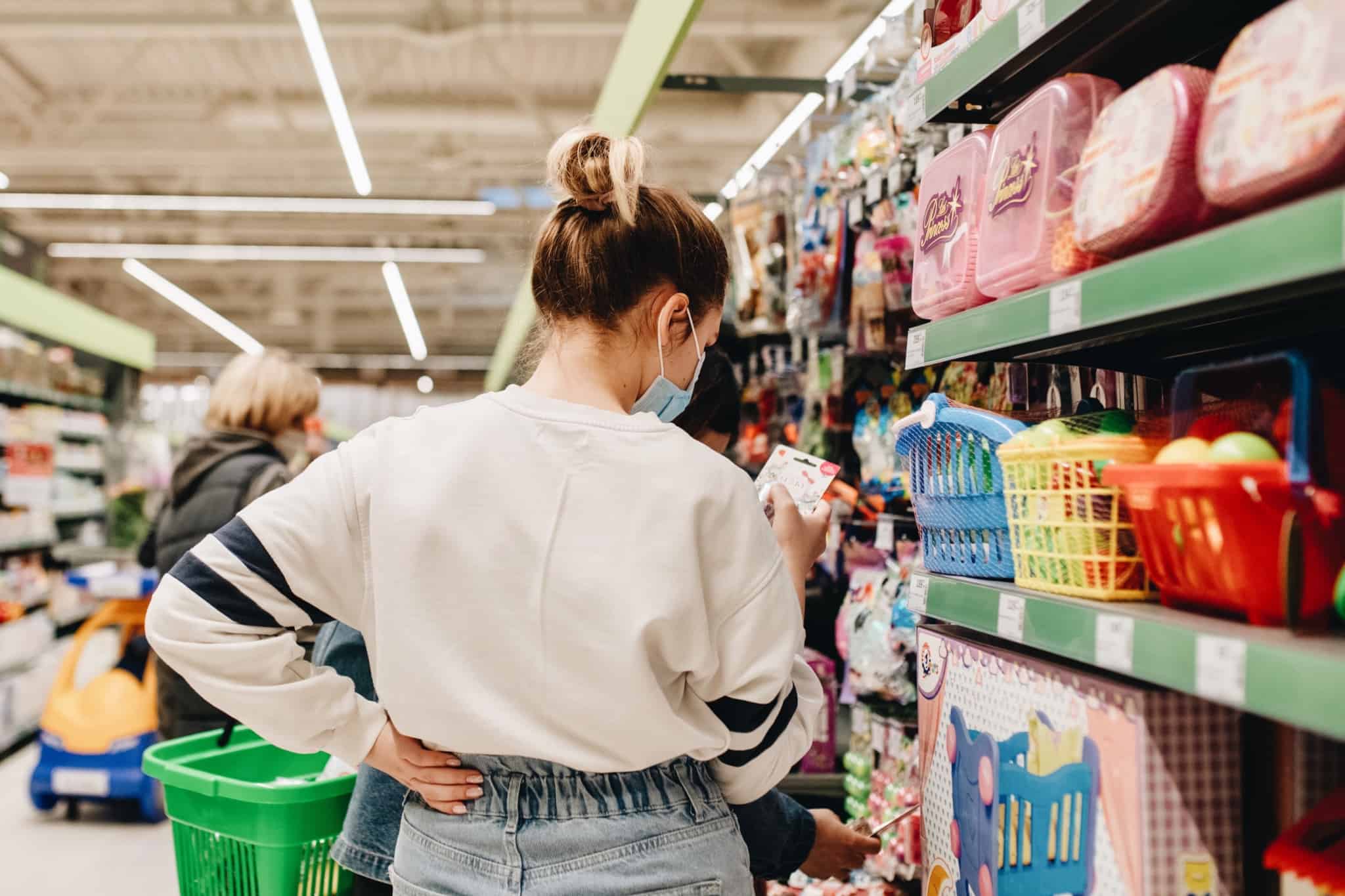 jovem mulher faz compra numa grande superfície e mostra-se a consultar preços e características dos produtos