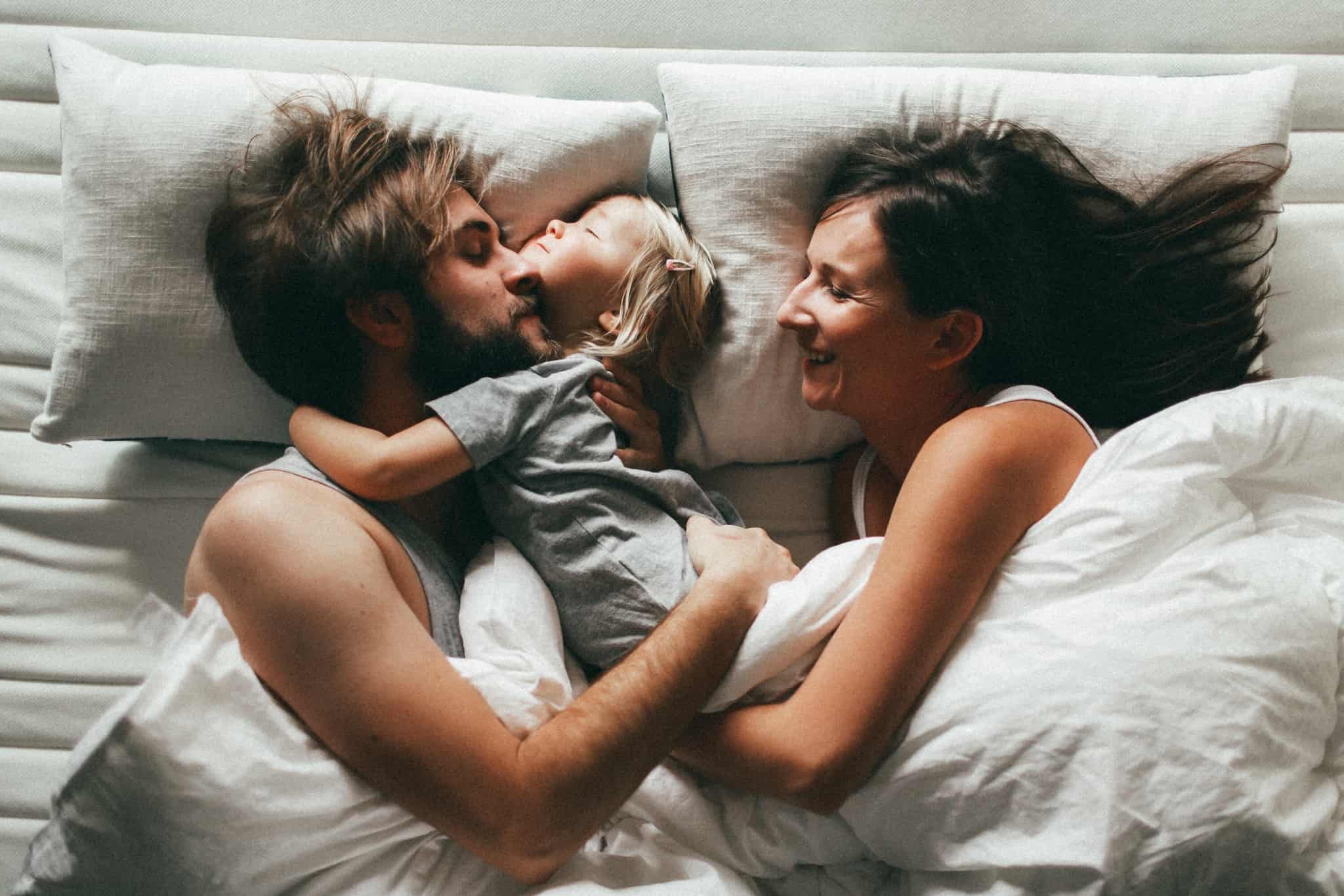 casal a brincar com a sua filha na cama. erros financeiros