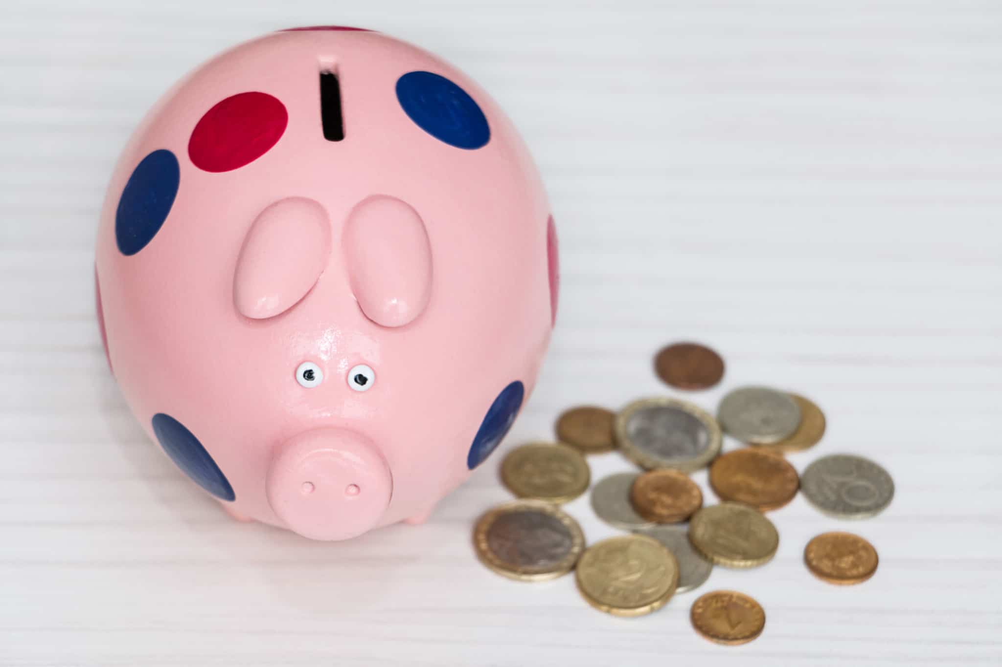 mealheiro em forma de porquinho com várias moedas de euro ao lado para serem colocadas no seu interior e constituir poupança