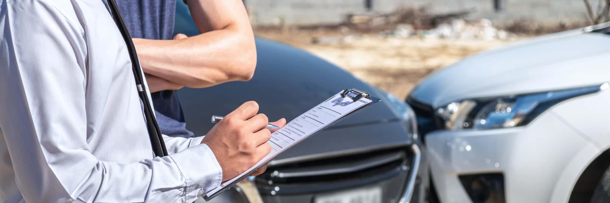 homem da seguradora e condutor preenchem ficha junto ao veículo acidentado a tratar do seguro automóvel