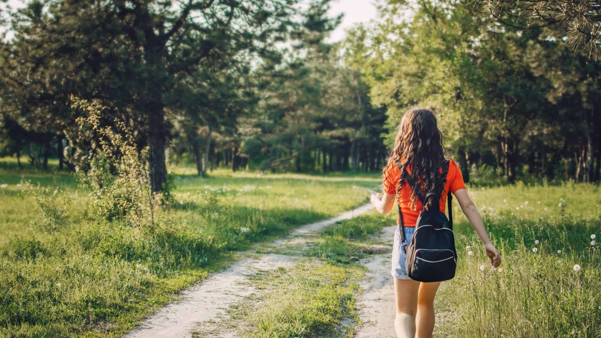 Jovem de mochila às costas, enquanto passeia numa floresta numa férias em famílias
