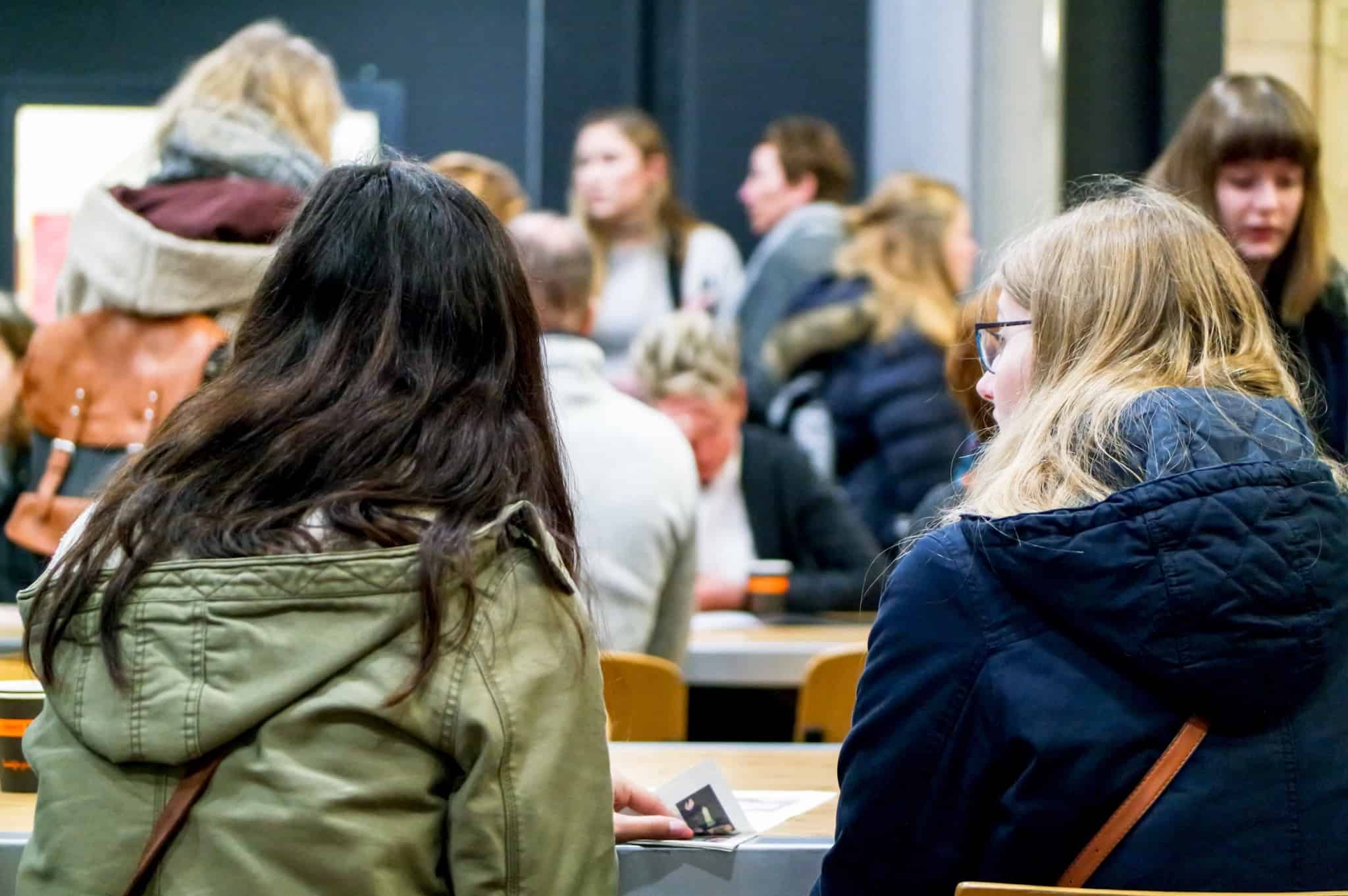 ambiente de universidade com um grupo vasto de jovens a falar e a conviver