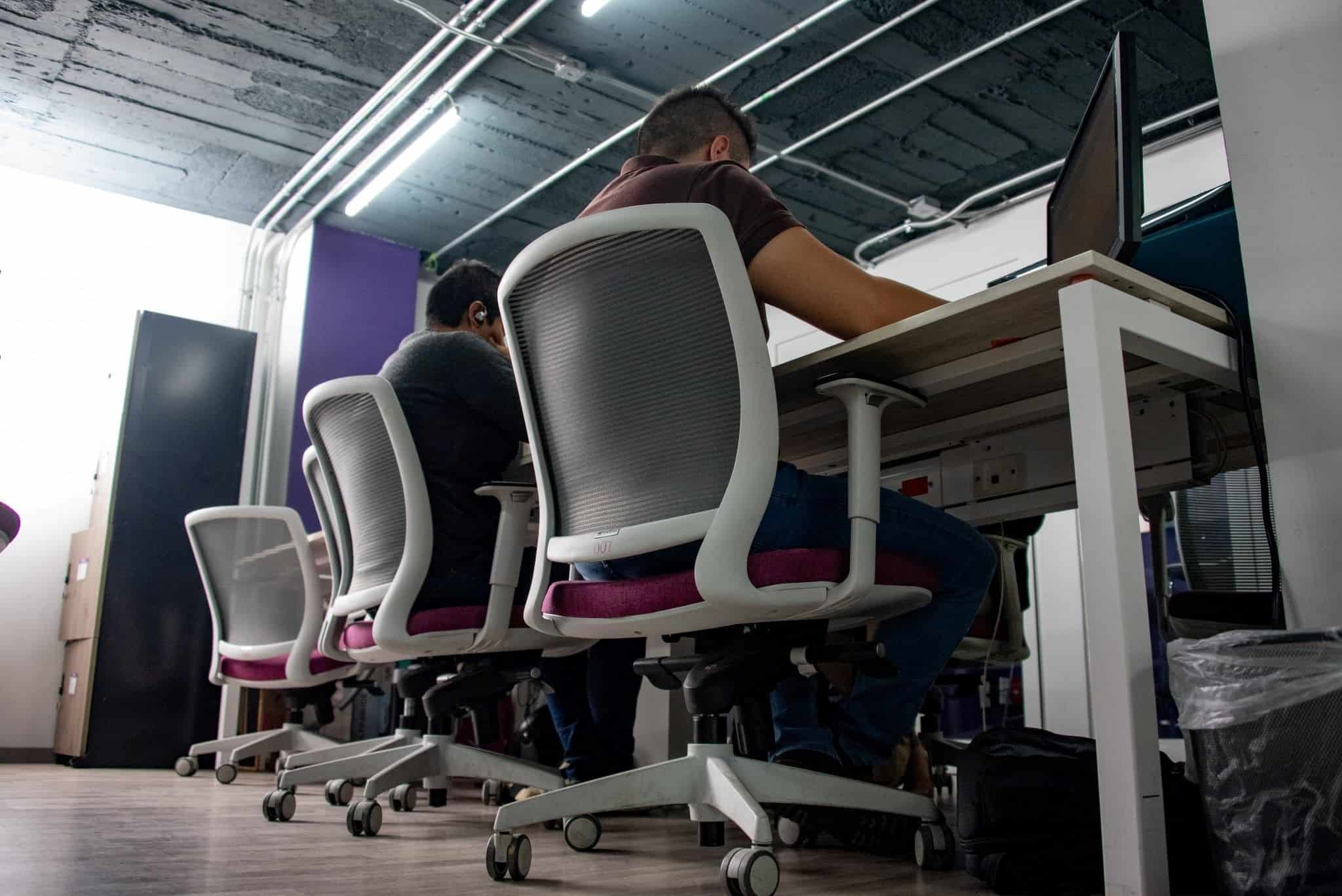 Trabalhadores sentados em cadeiras de escritório de costas