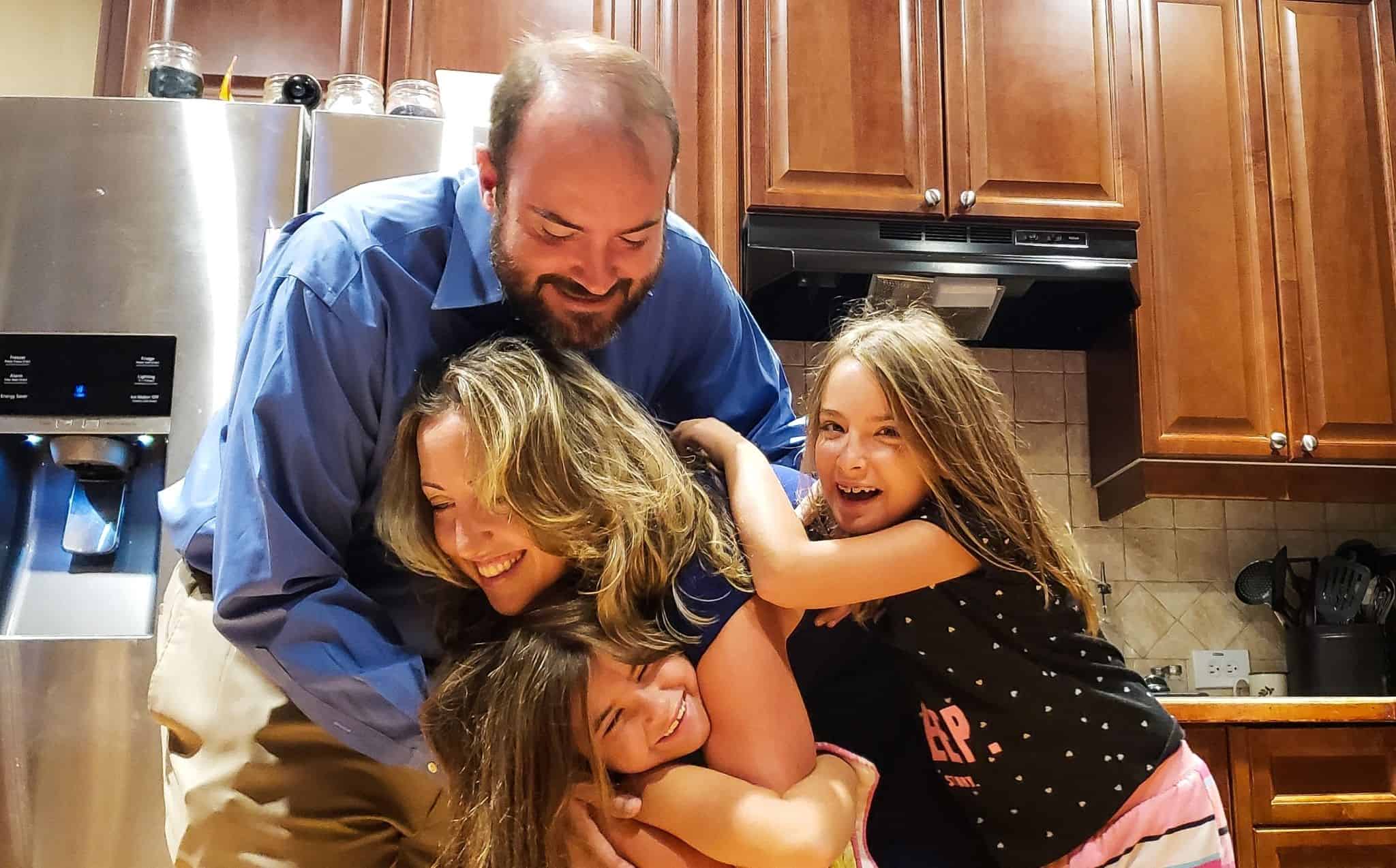 Família a abraçar-se na cozinha evocando as moratórias