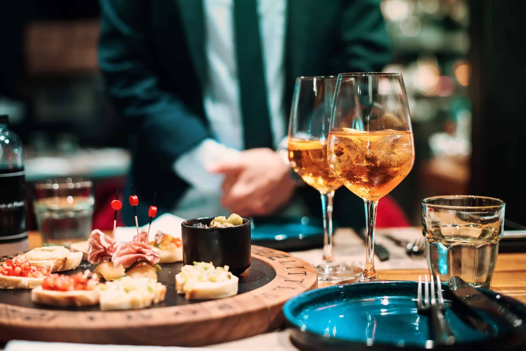 mesa posta num restaurante, um dos espaços envolvidos no IVAucher, com dois copos servidos e uma tábua de tapas variadas.