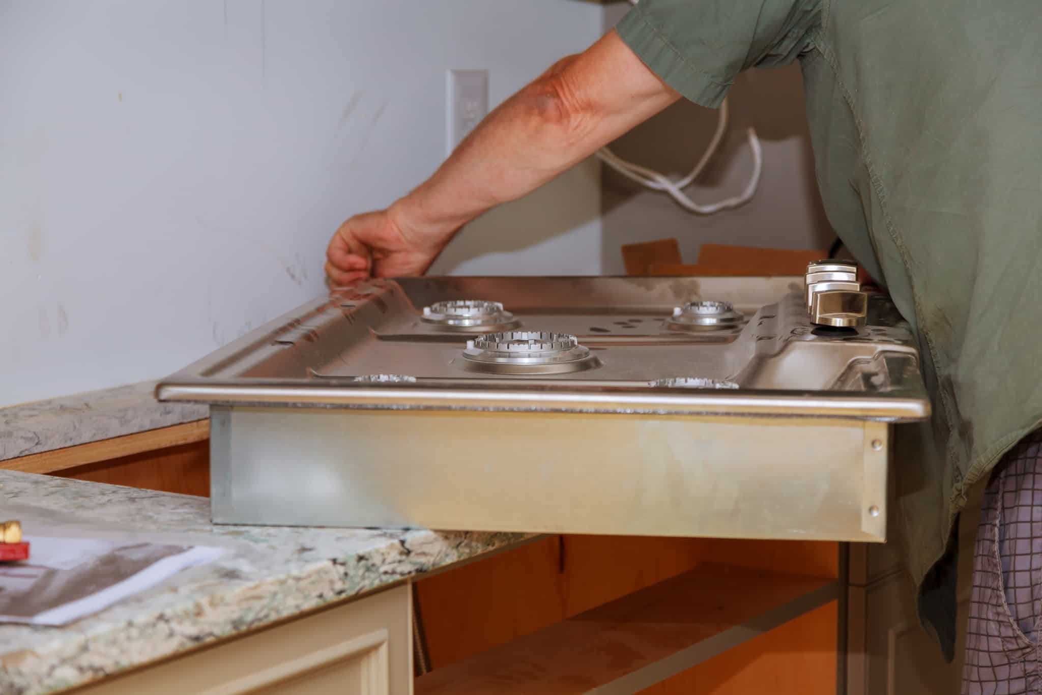homem trata da inspeção de gás e colocação do fogão na respetiva bancada da cozinha