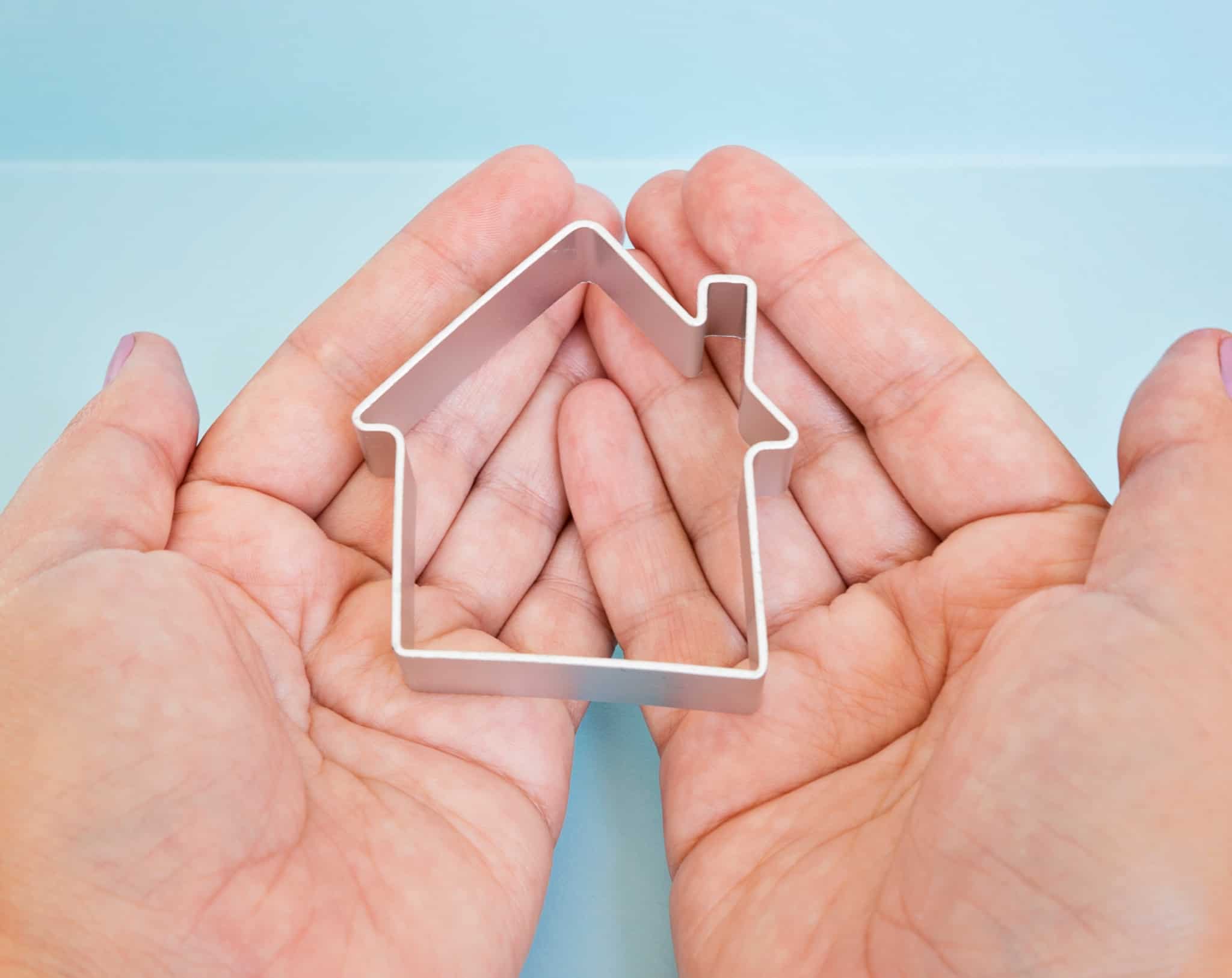 produção fotográfica meramente ilustrativa. mãos seguram uma pequena maqueta de uma casa, simbolizando uma segura