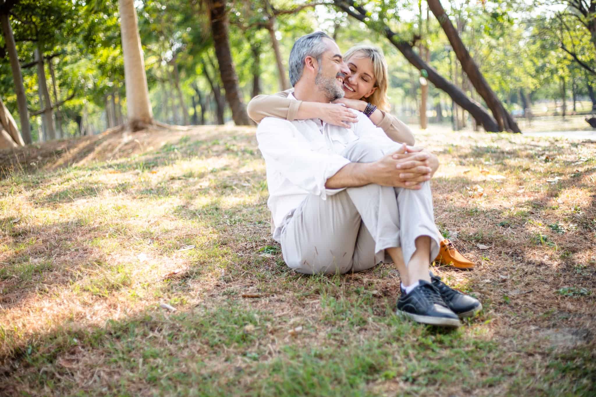 casal de meia idade descansa numa zona verde, num parque, aproveitando o seu tempo de pré-reforma.