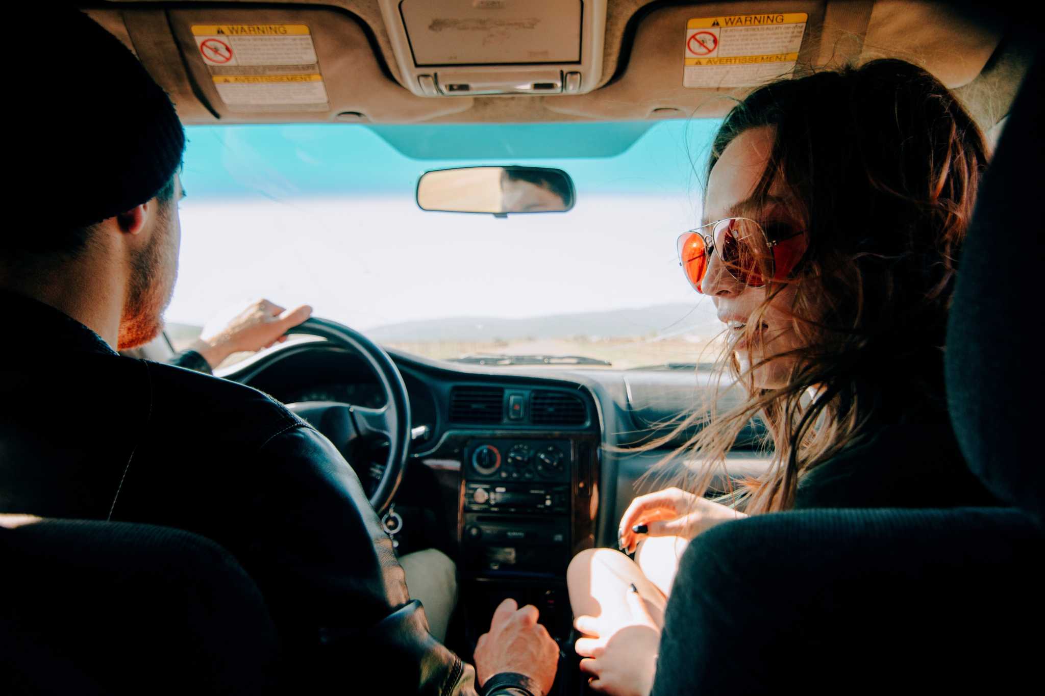 jovem casal, em viagem no seu automóvel, bem dispostos, a aproveitar a viagem
