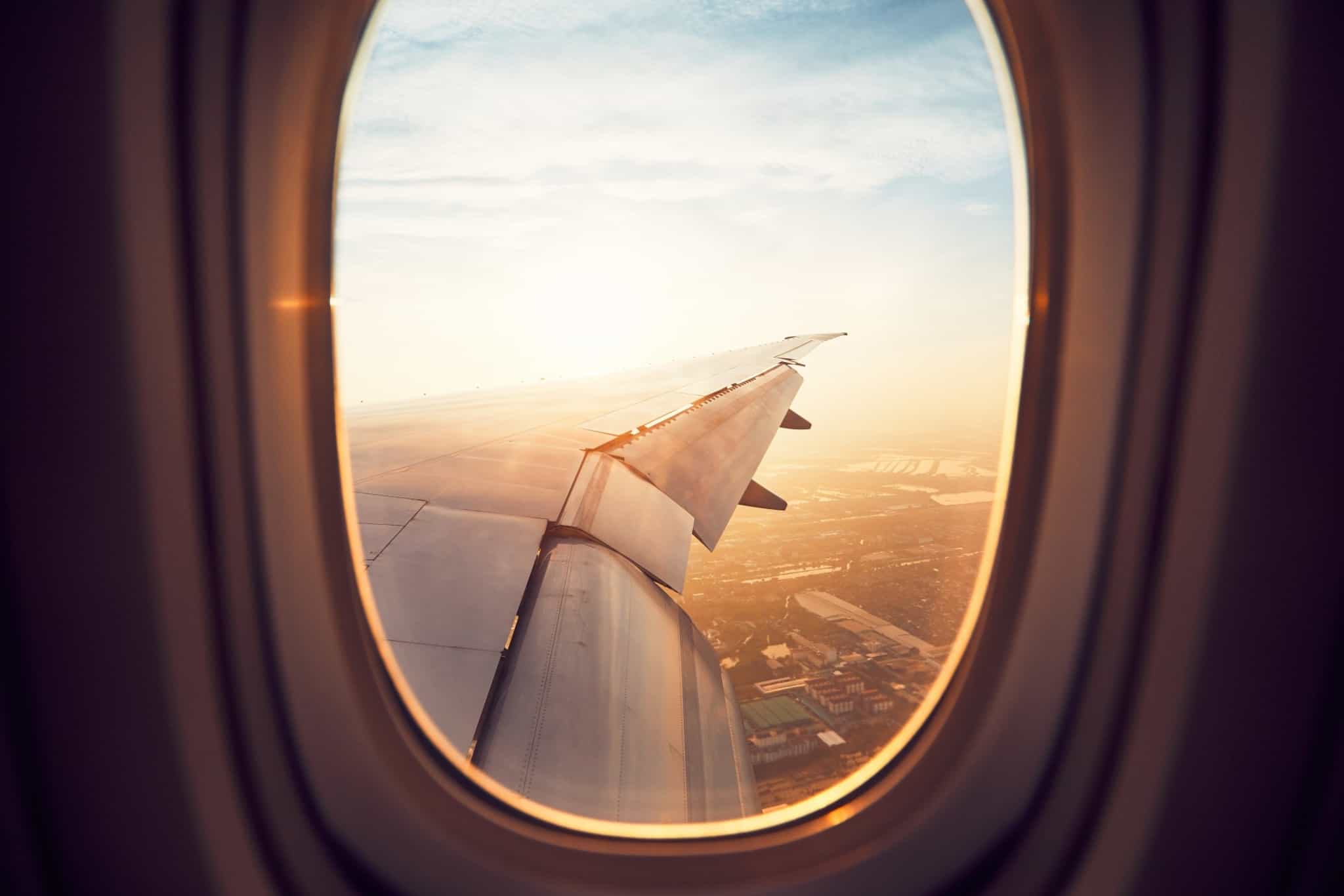 Asa de avião vista da janela com uma cidade com casas por baixo
