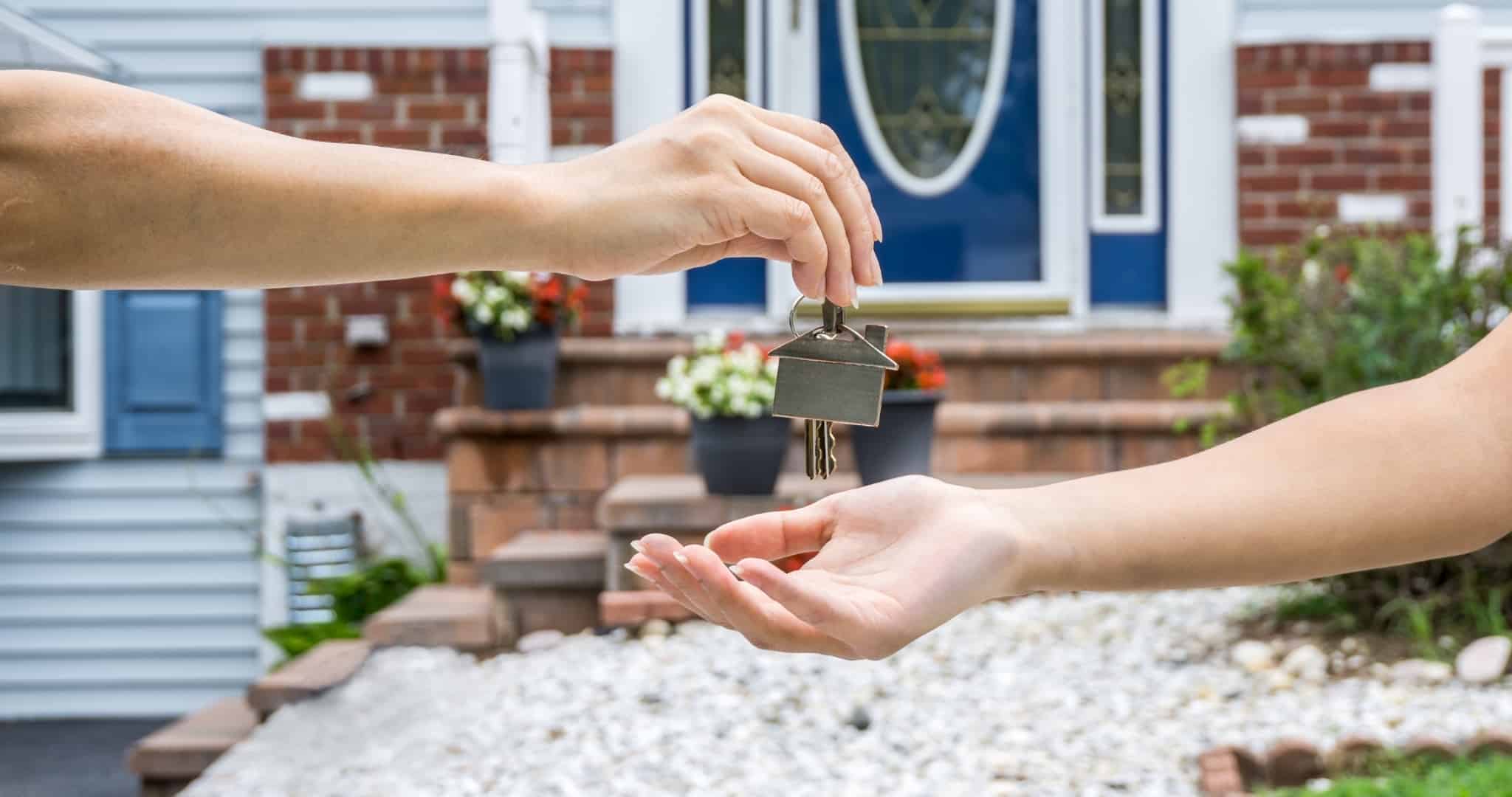Uma mão a entregar uma chave a outra para arrendamento acessível de casa