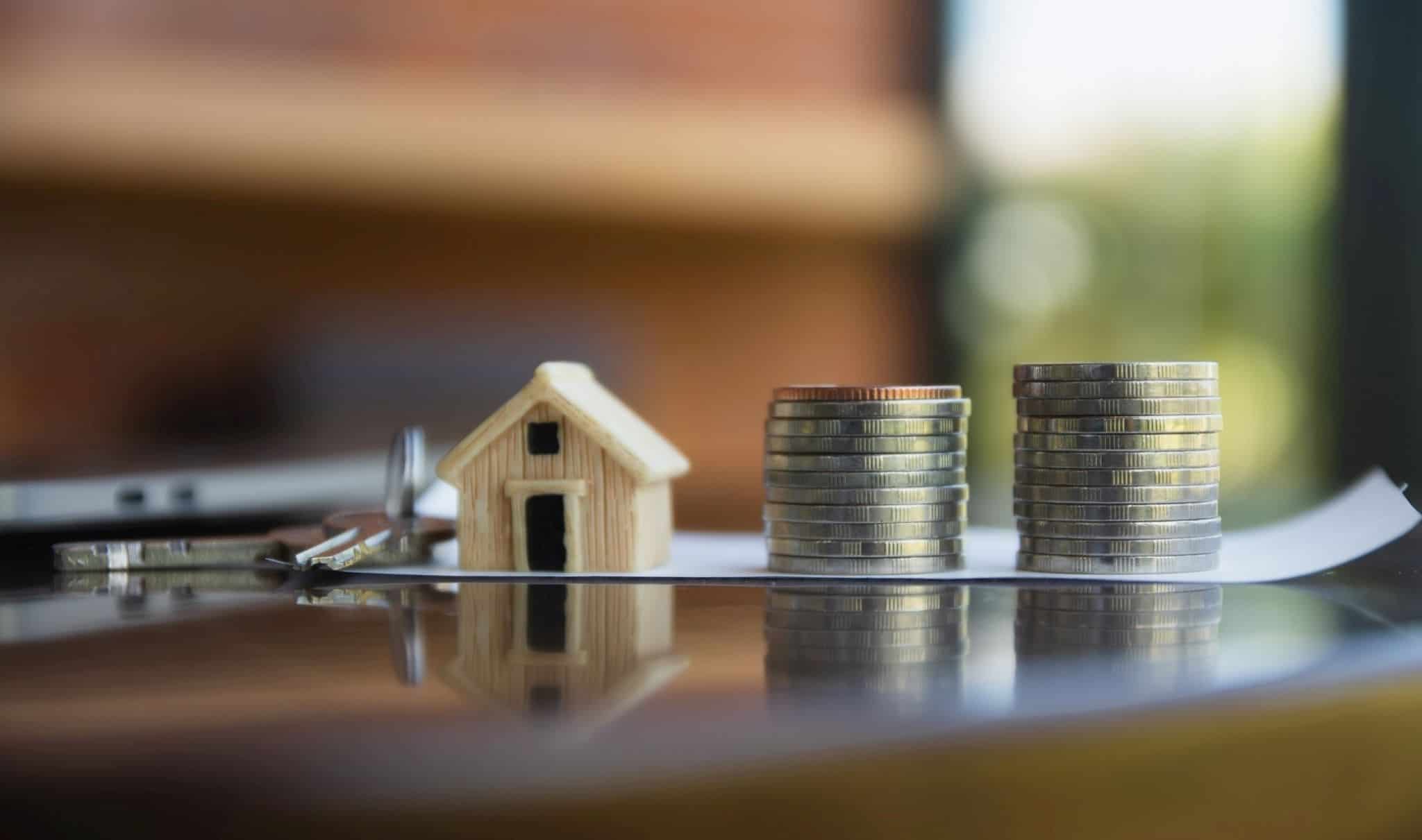 Casa de brincar e moedas em cima de um contrato de moratória de crédito