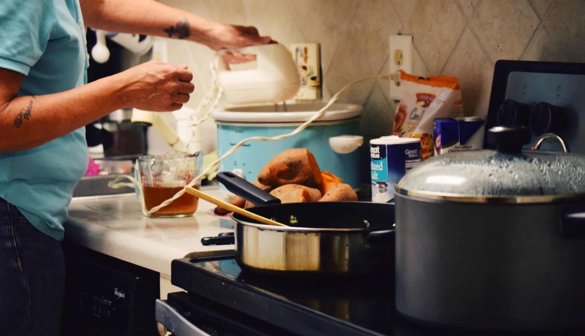 Pessoa na cozinha a faezr refeição e um bolo
