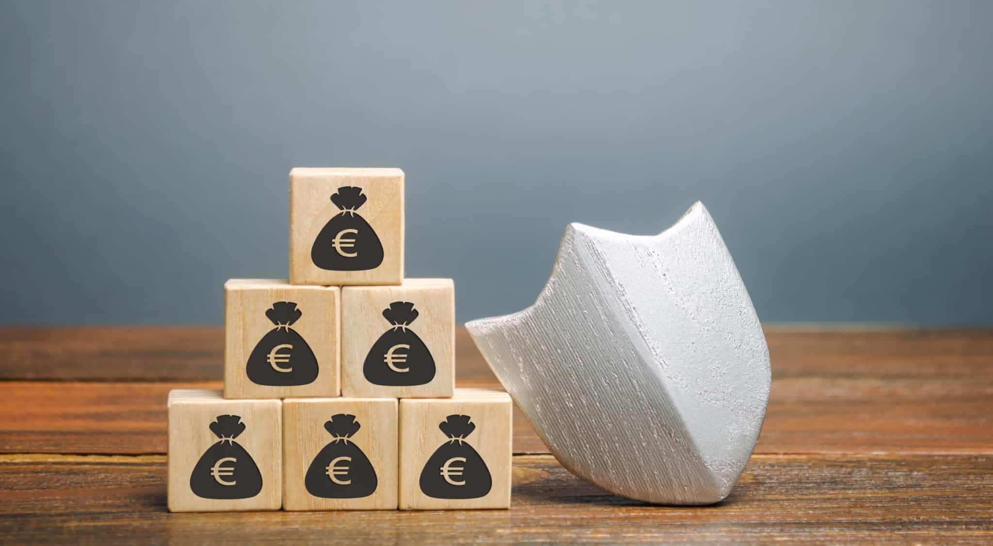 blocos de madeira com o desenho de um saco com um símbolo de euro, que ilustra a poupança e o salário real