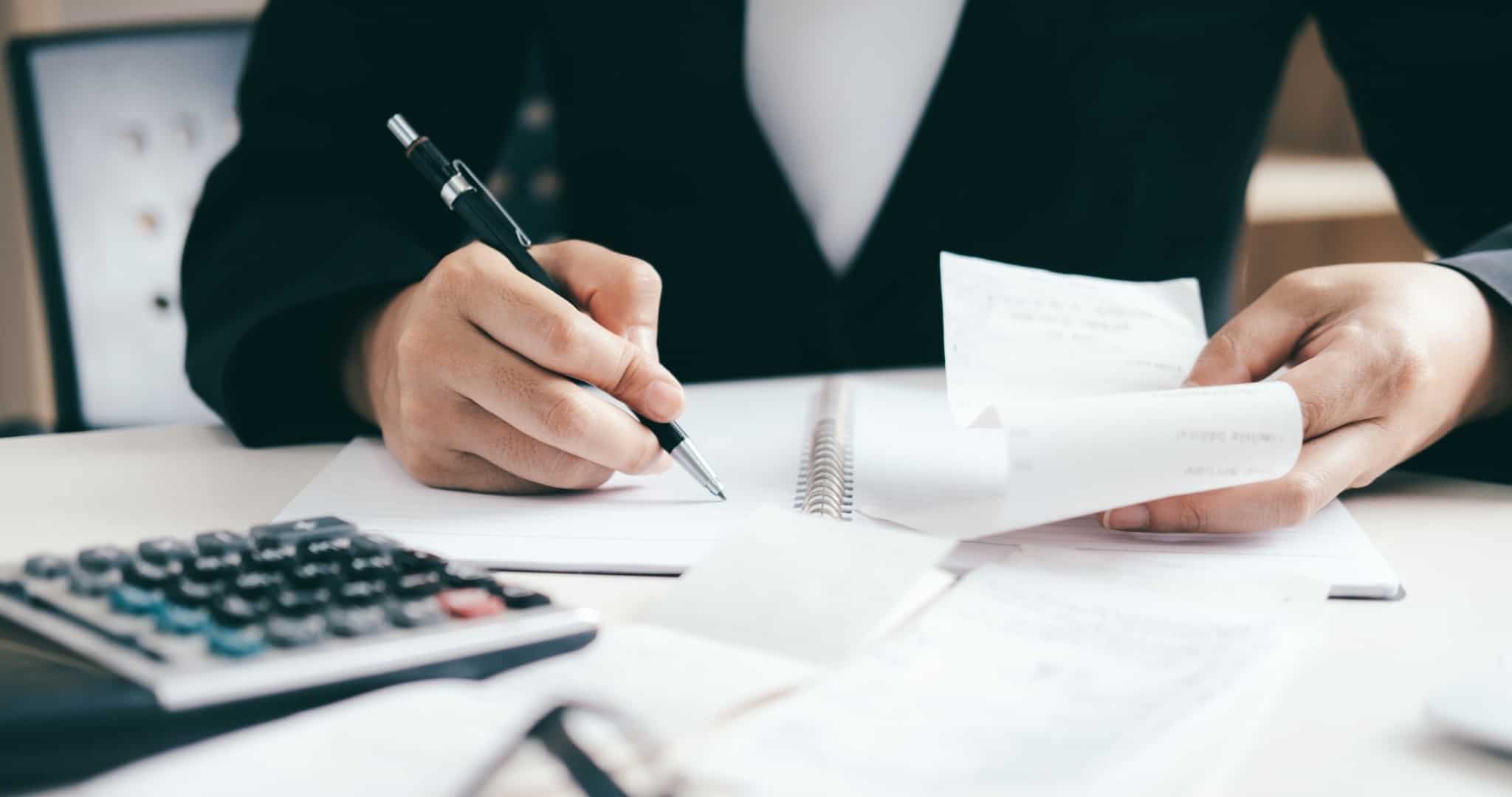 Contabilista a fazer contas com papel caneta e calculadora, a mostrar vantagens de contabilidade para empresas