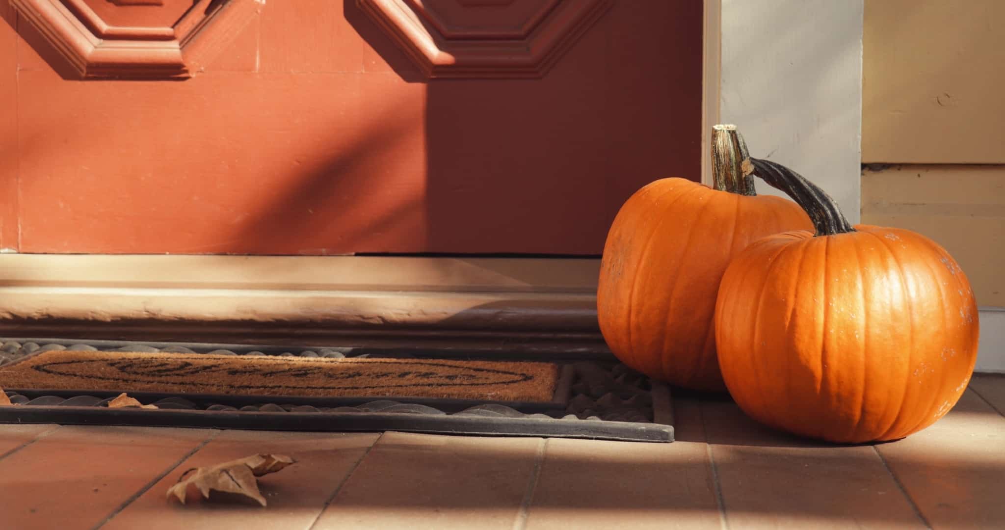Duas abóboras no chão à porta de uma casa a decorar pelo Halloween