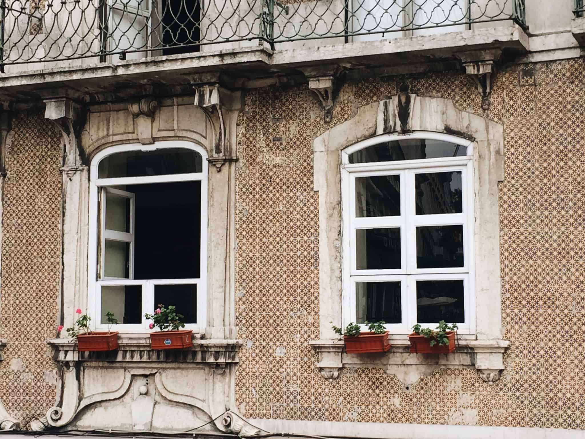 imagem com parte de uma fachada de um prédio antigo de Lisboa com duas janelas típicas