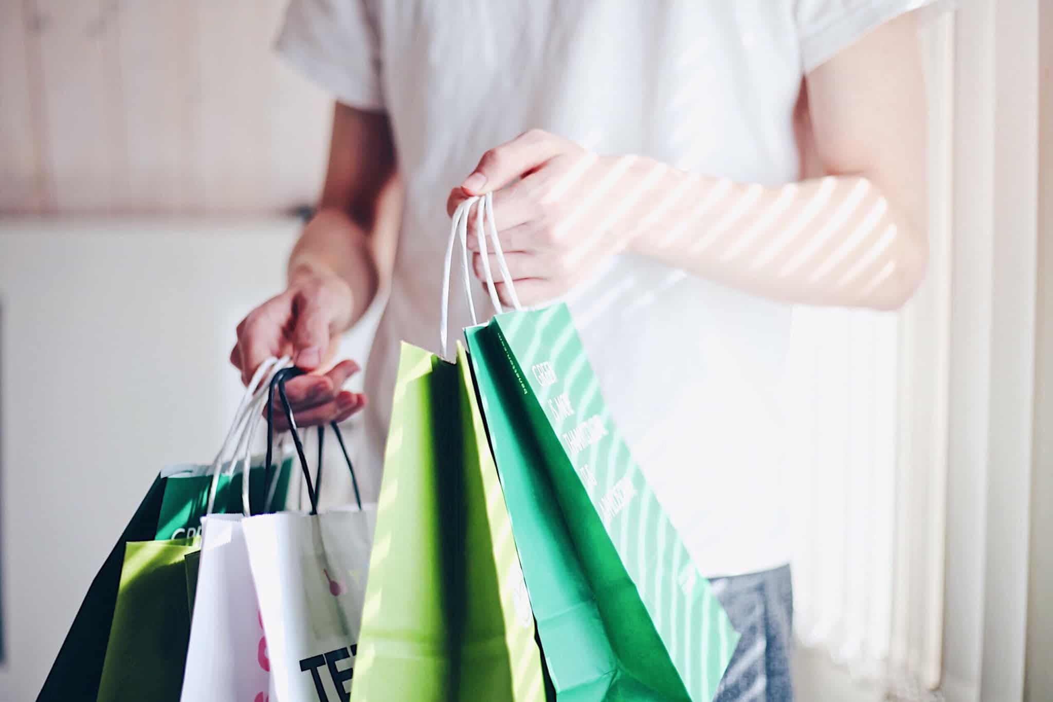 compras e dicas de poupança ilustradas por uma produção fotográfica que mostra a mão de uma jovem que segura muitos sacos de compras