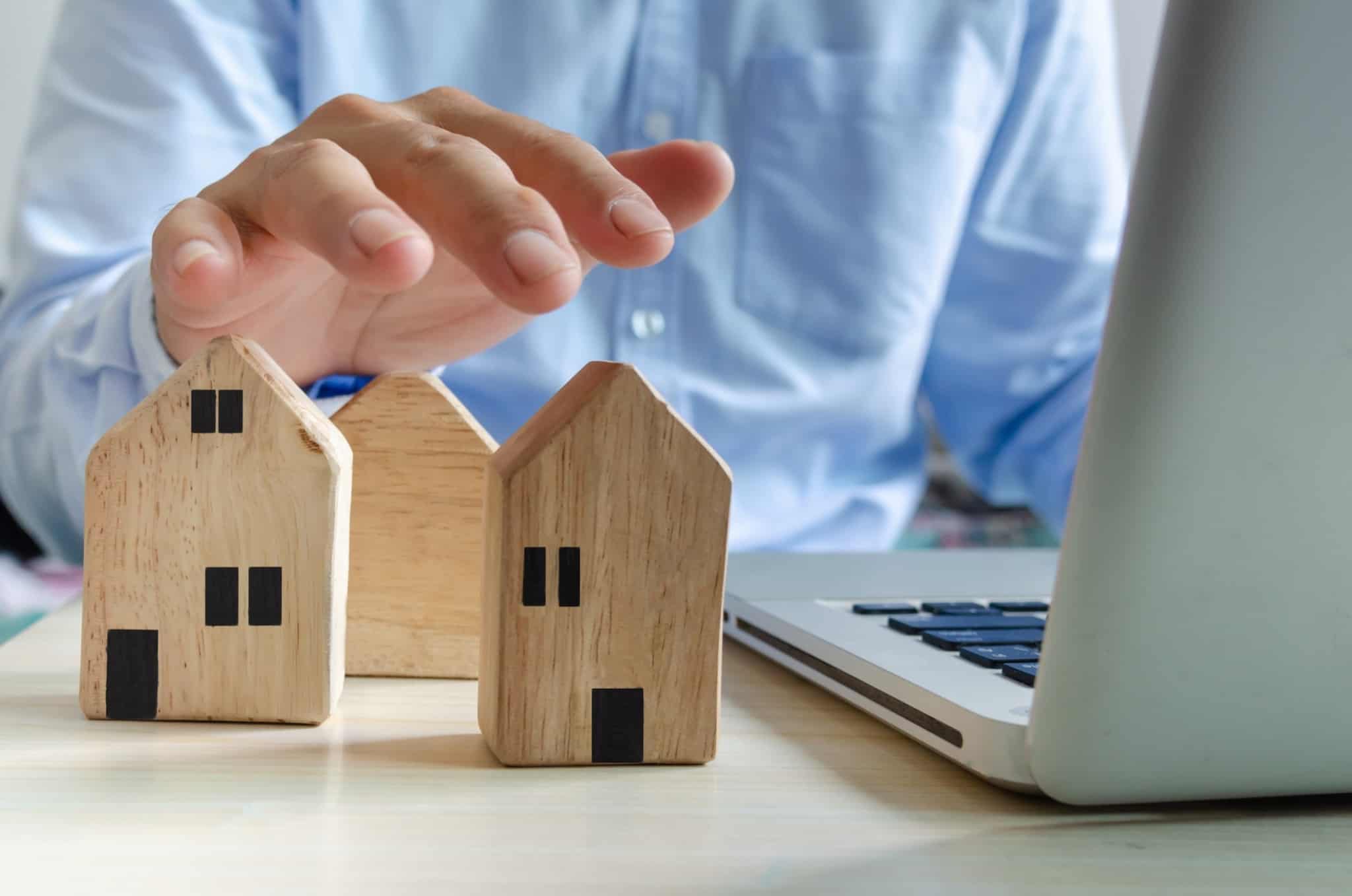 miniaturas de prédios, em madeira, ao lado de um computador, numa alusão ao investimento em fundos imobiliários