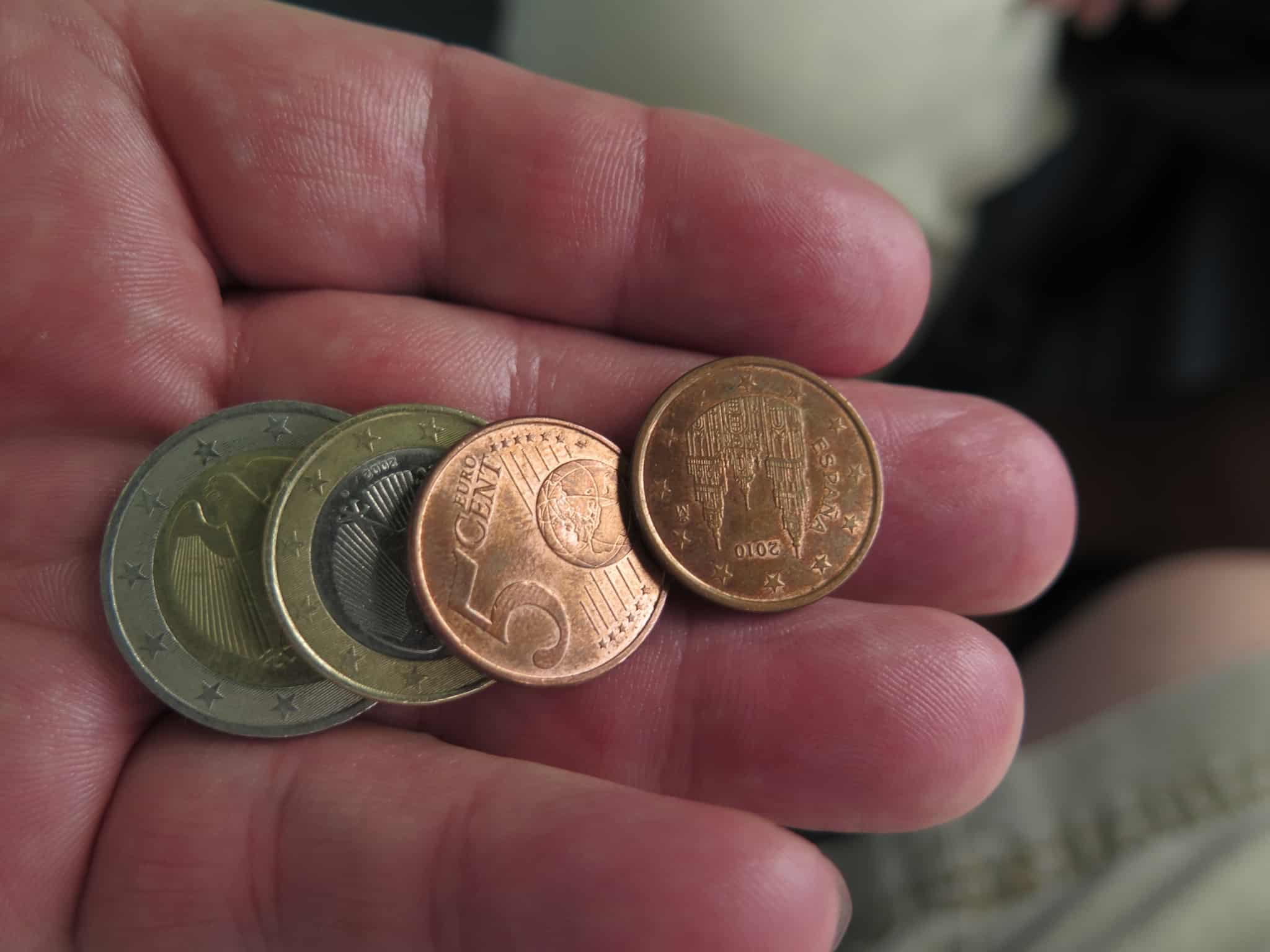 conceitos económicos como a inflação e deflação ilustrados com a imagem de uma mão com algumas moedas de euro, remetendo para o poder de compra das pessoas