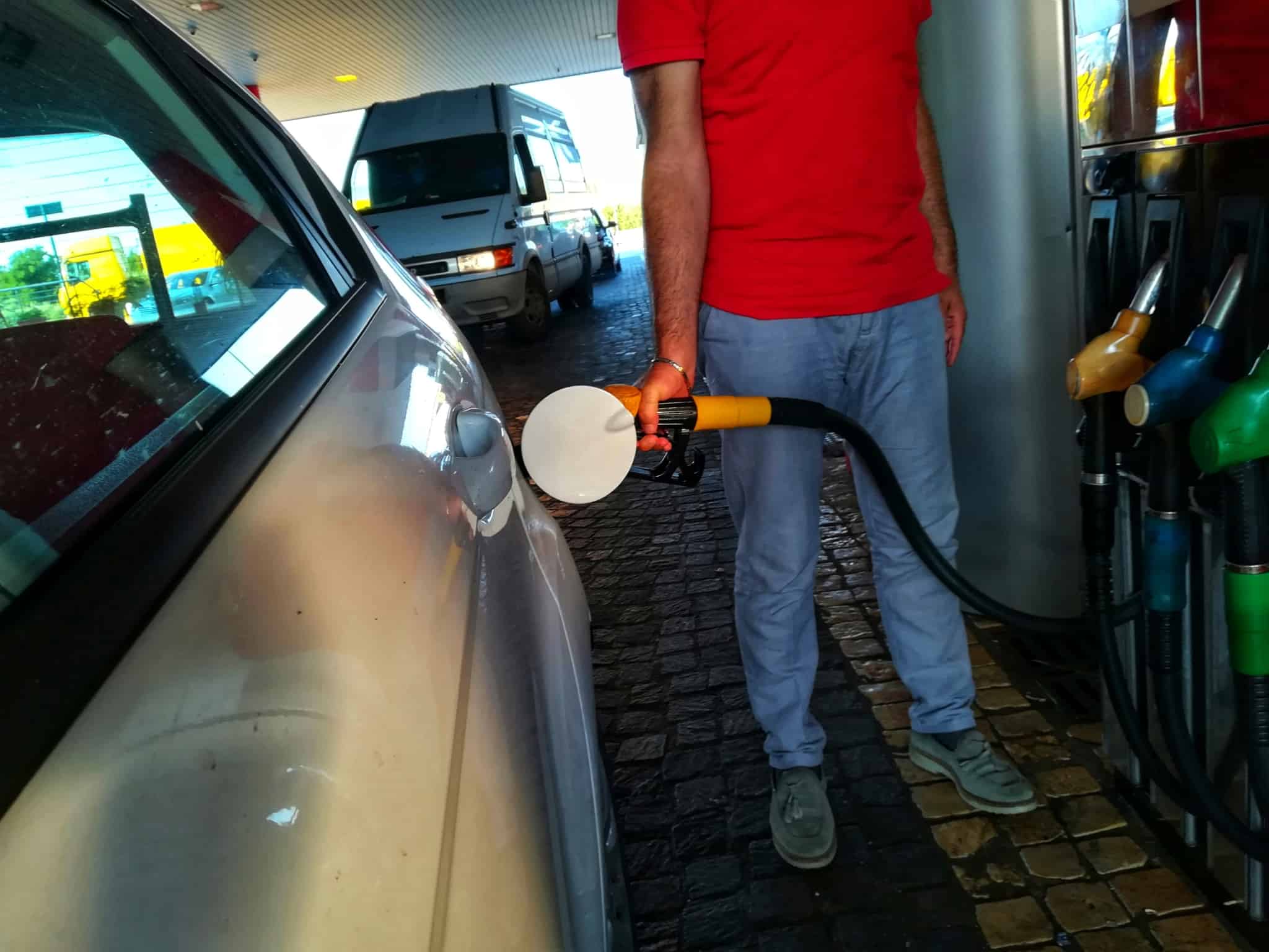 homem, na bomba de gasolina, abastece o seu automóvel