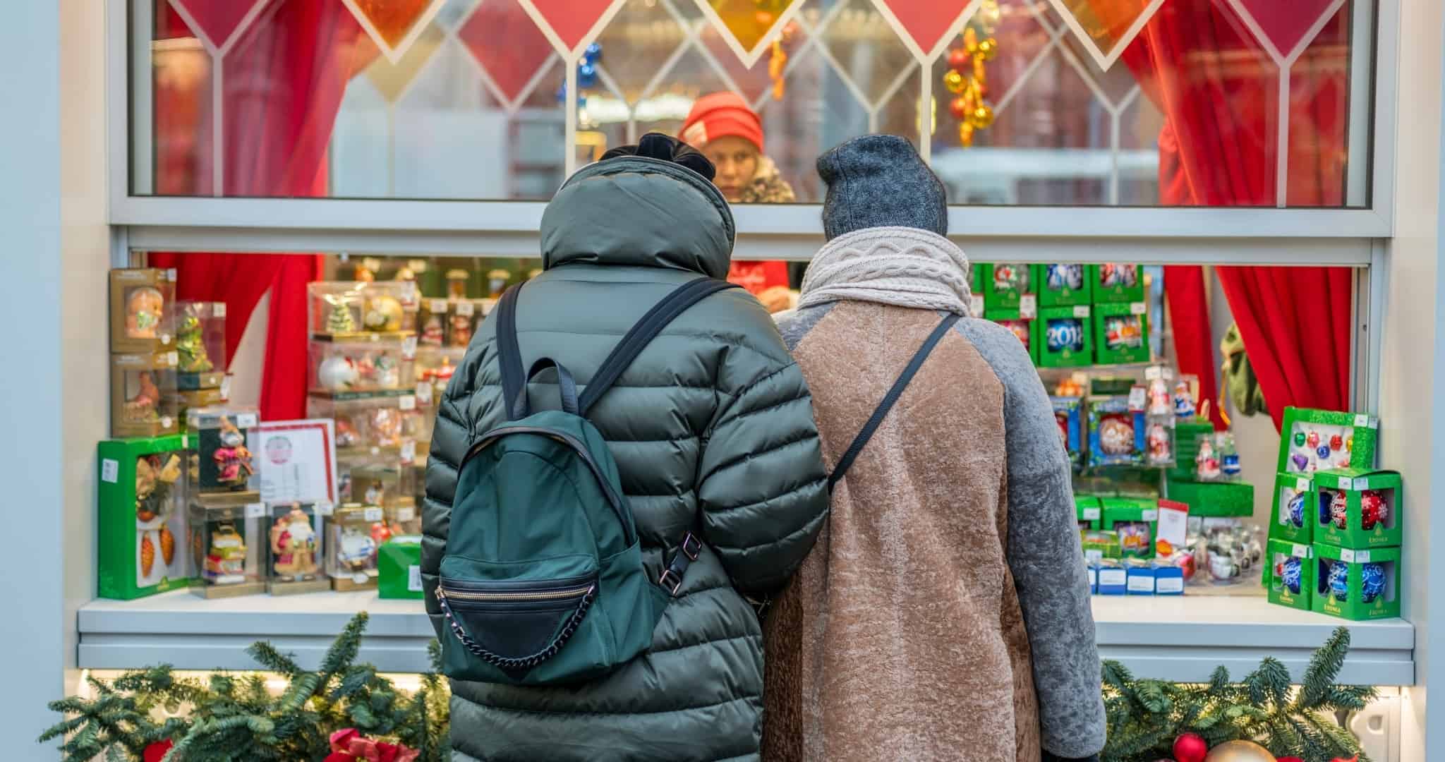 Casal em frente a montra de Natal a comprar presentes