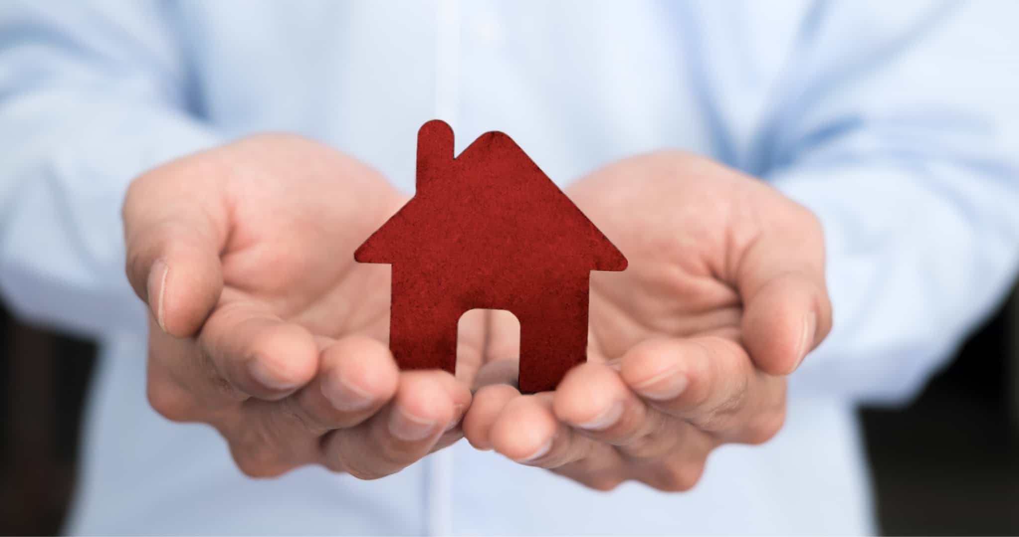 Mãos de homem a segurar peça em madeira de casa a simbolizar crédito habitação