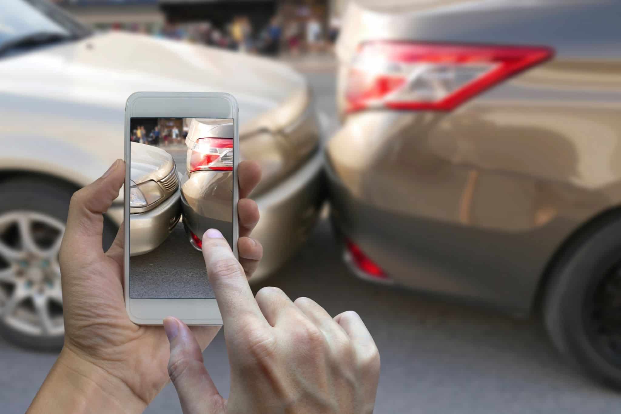 Mãos tiram fotografia de acidente para preencher declaração amigável
