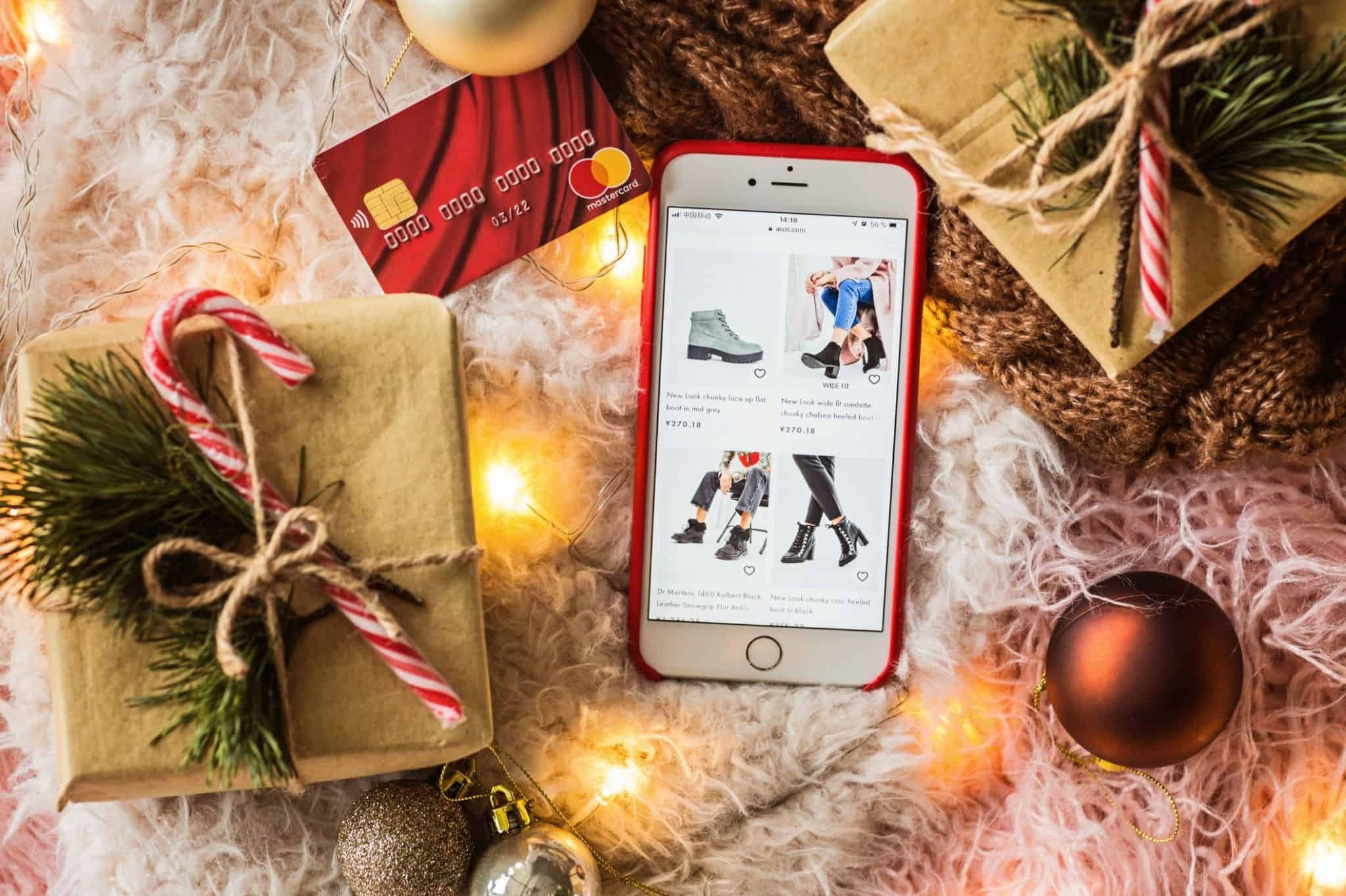 Imagem a representar as compras de natal - smartphone com uma loja online, um cartão bancário, vários presentes de natal e adereços