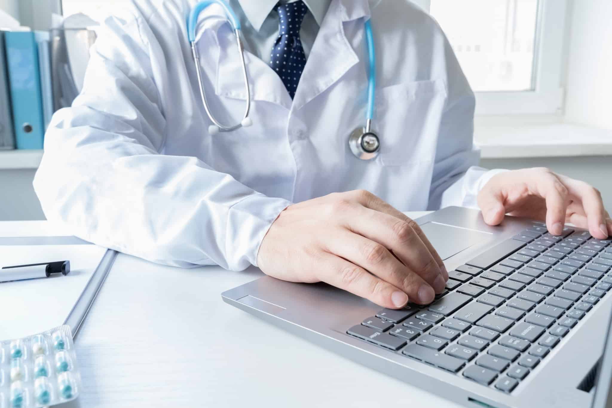 Imagem de um médico ao computador em contexto de consula - seguro e plano de saúde