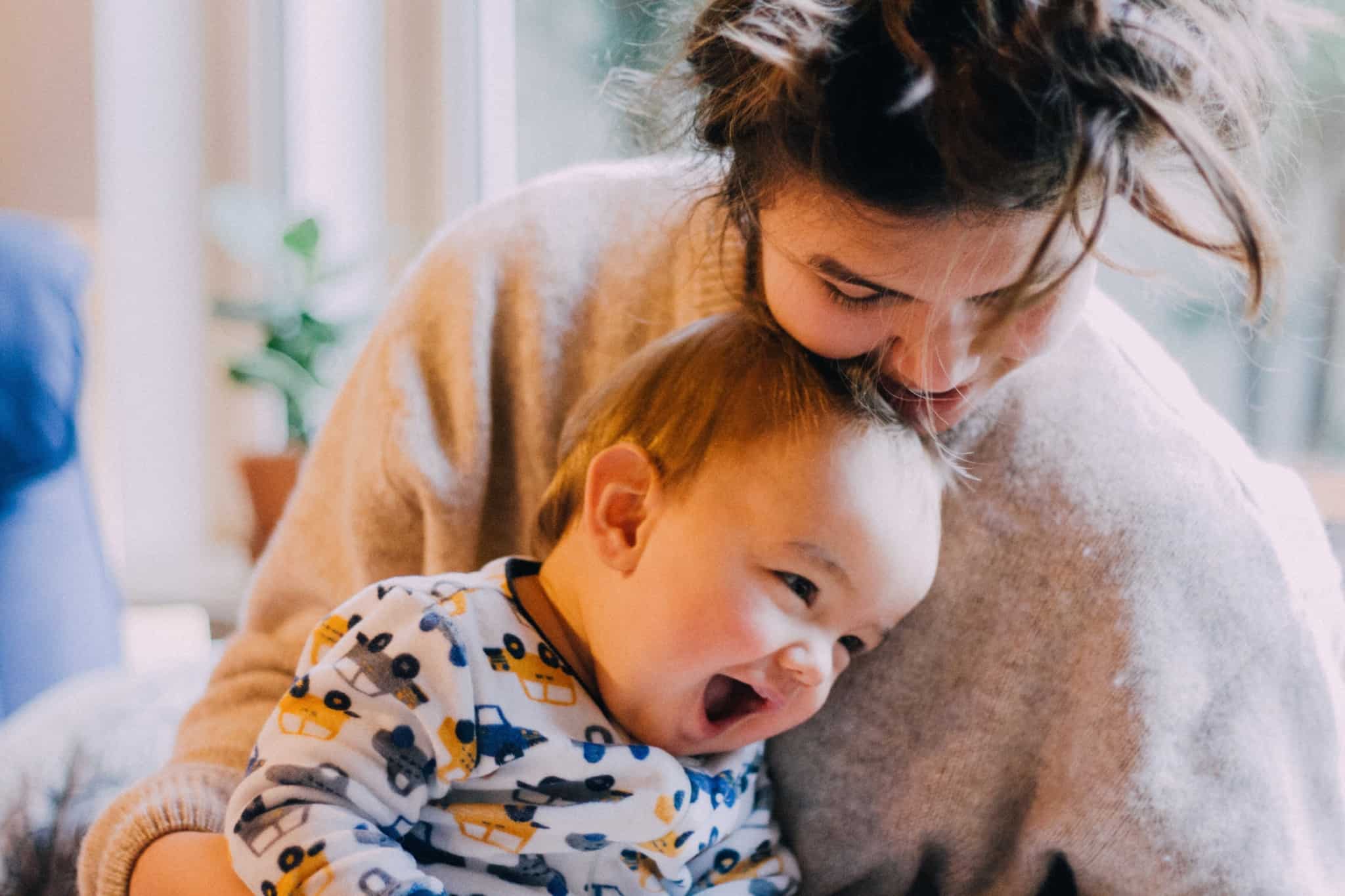 jovem mãe com o seu bébe, muito sorridente, ao colo