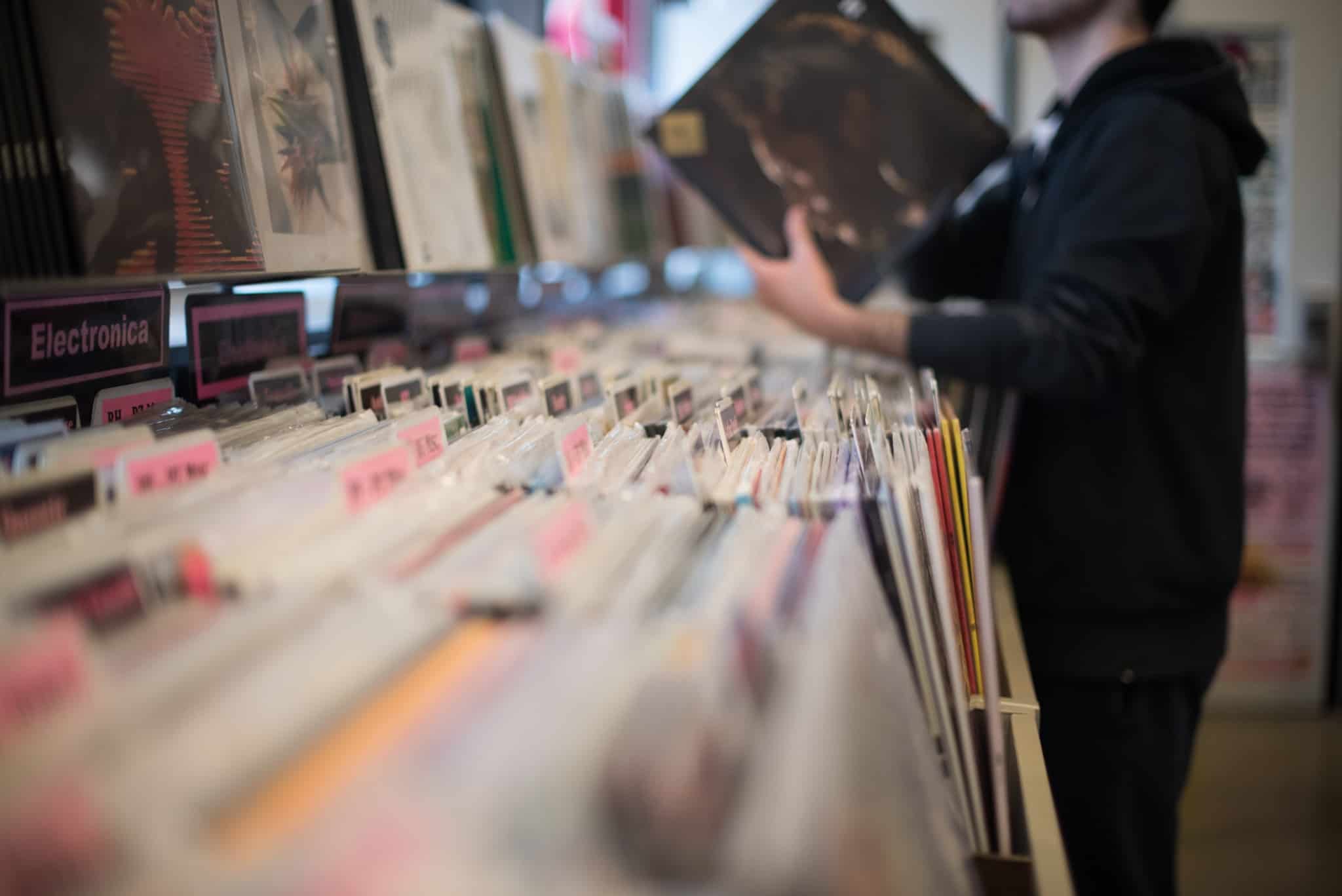 jovem rapaz em loja de discos antigos, em vinil