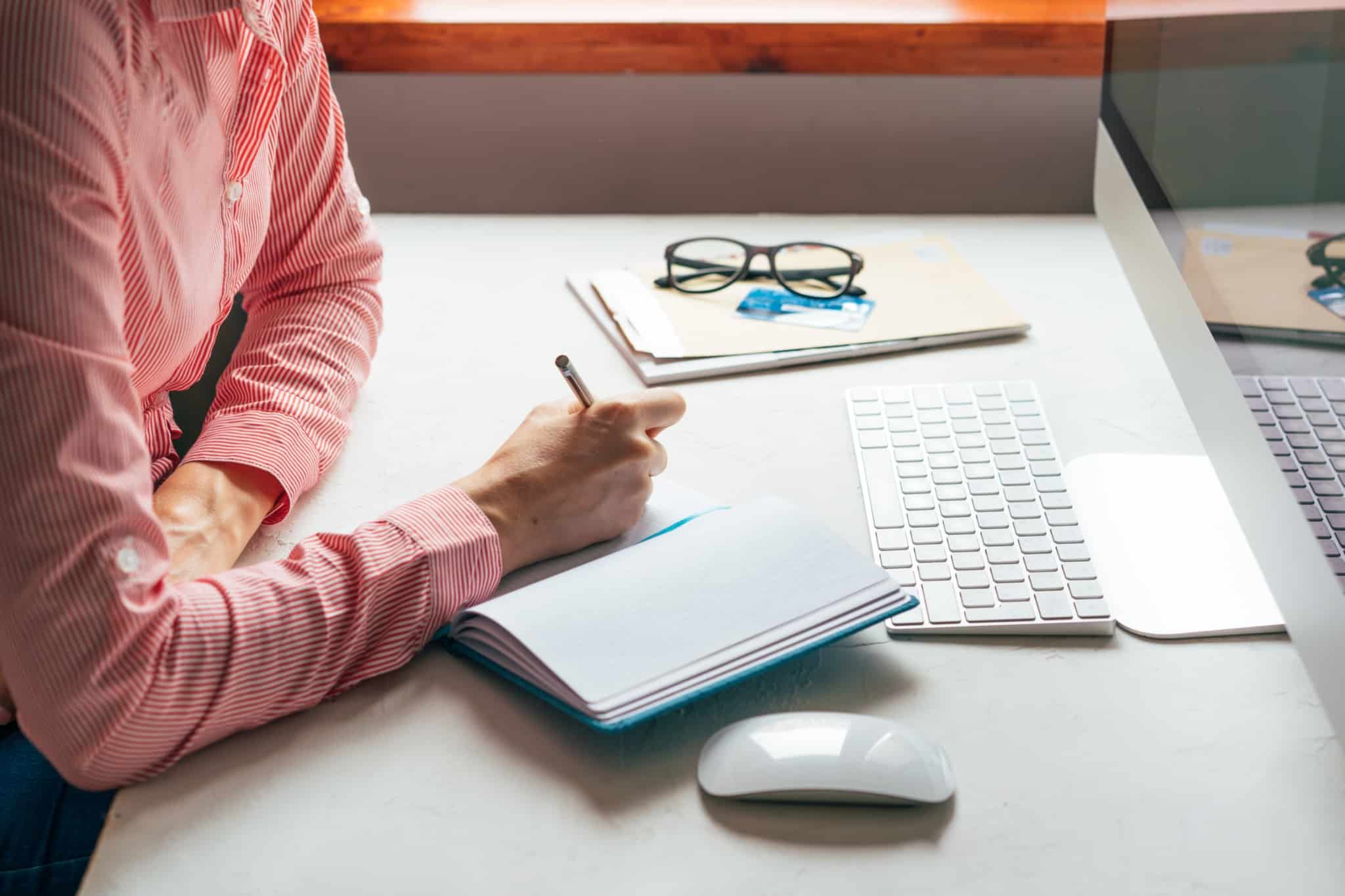homme faz contas aos encargos mensais, apontando tudo num caderno