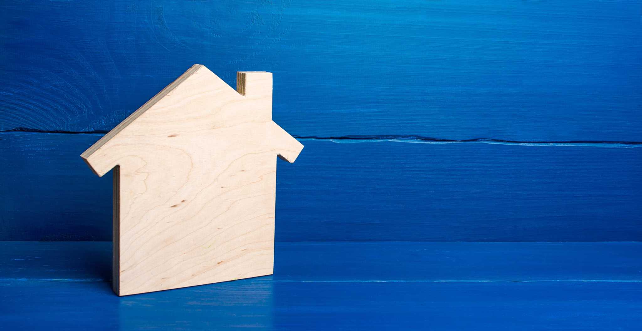 investimento imobiliário ilustrado com produção fotográfica que mostra uma casa em madeira , em fundo azul, liso