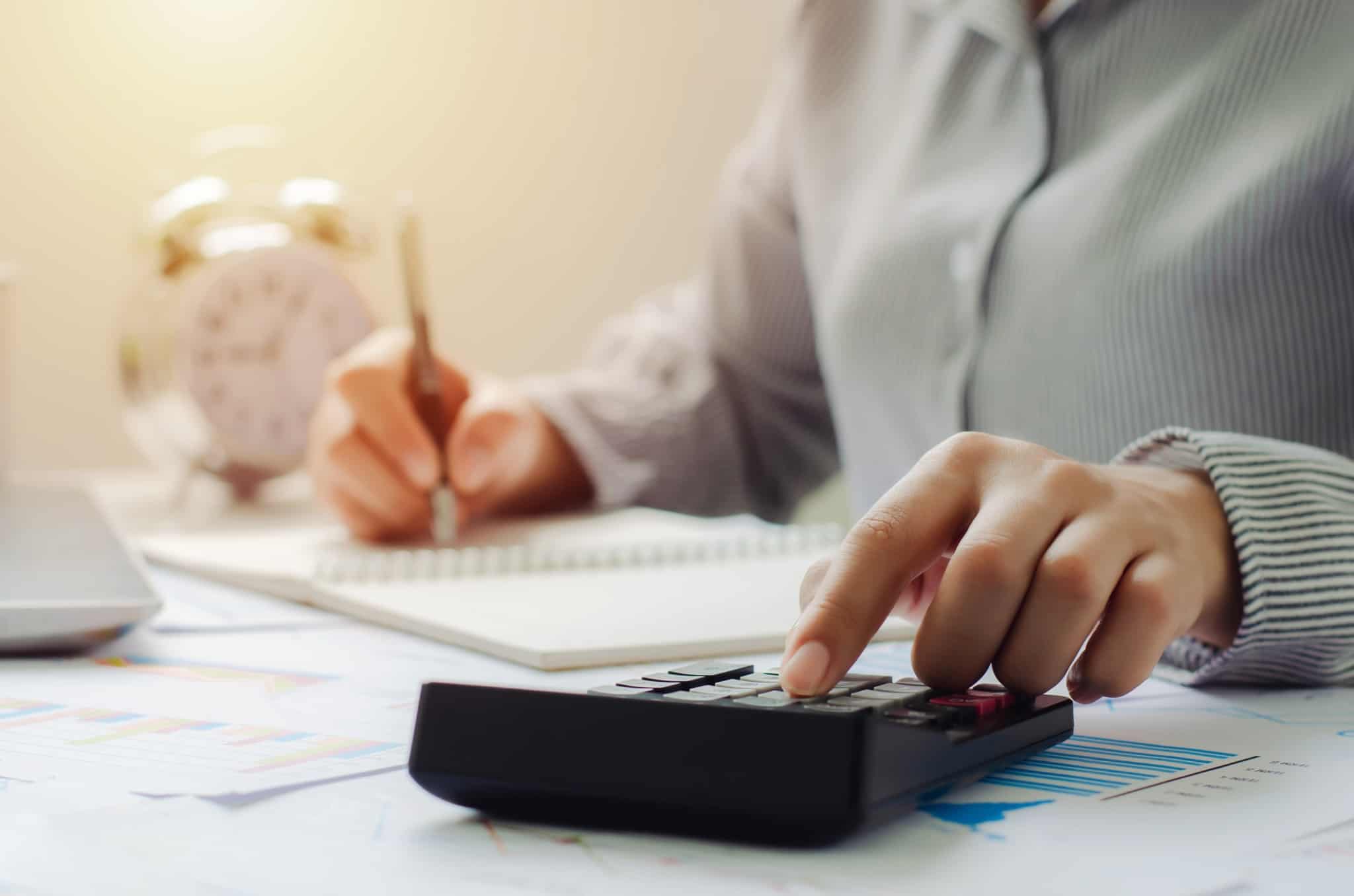 jobem mulher consulta contas e com o apoio da calculadora estuda como pode gerir um só salário para a sua família