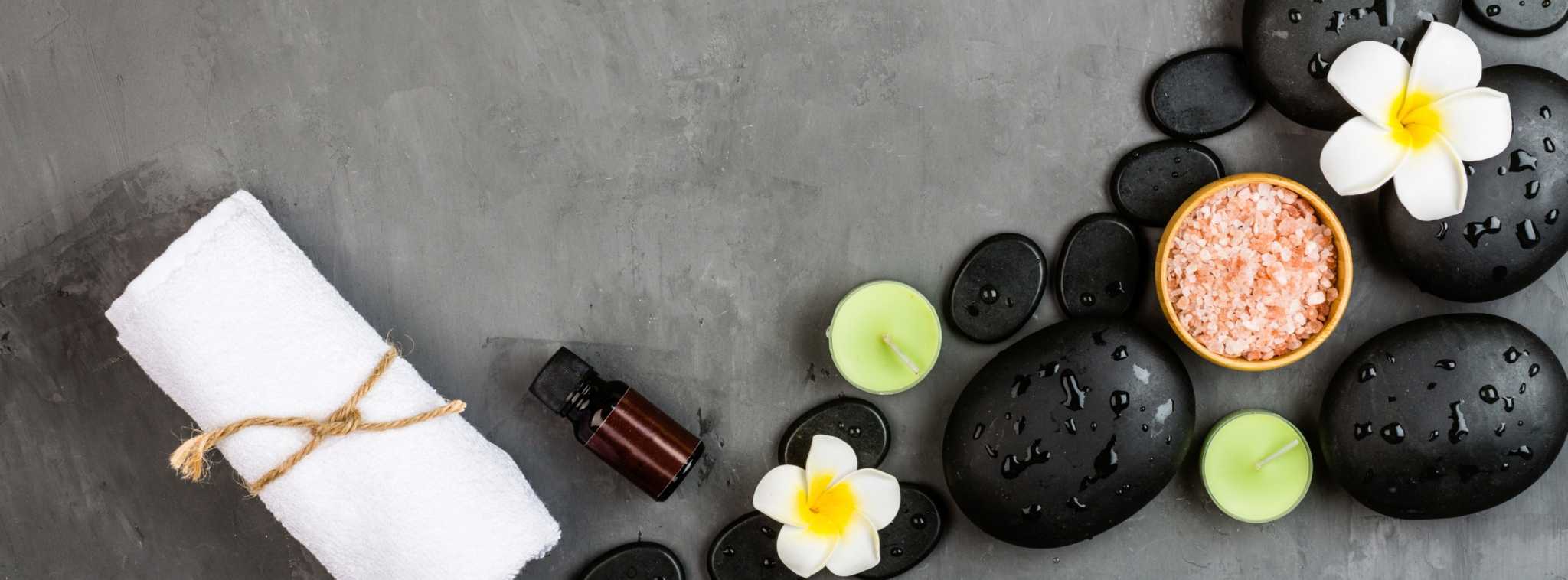 pedras de spa dispostas no chão rodeada de flores num experiência para ter uma vida mais feliz