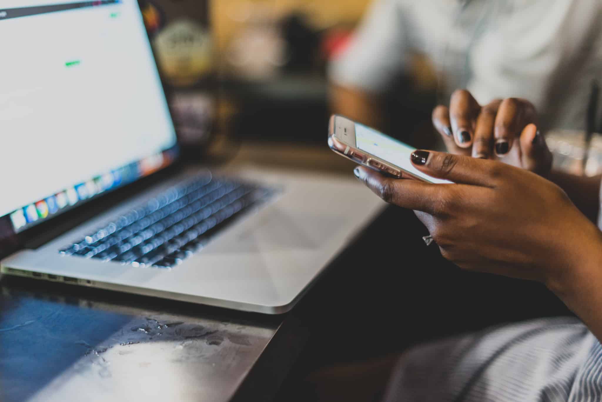 jovem usa o smartphone e o computador portátil