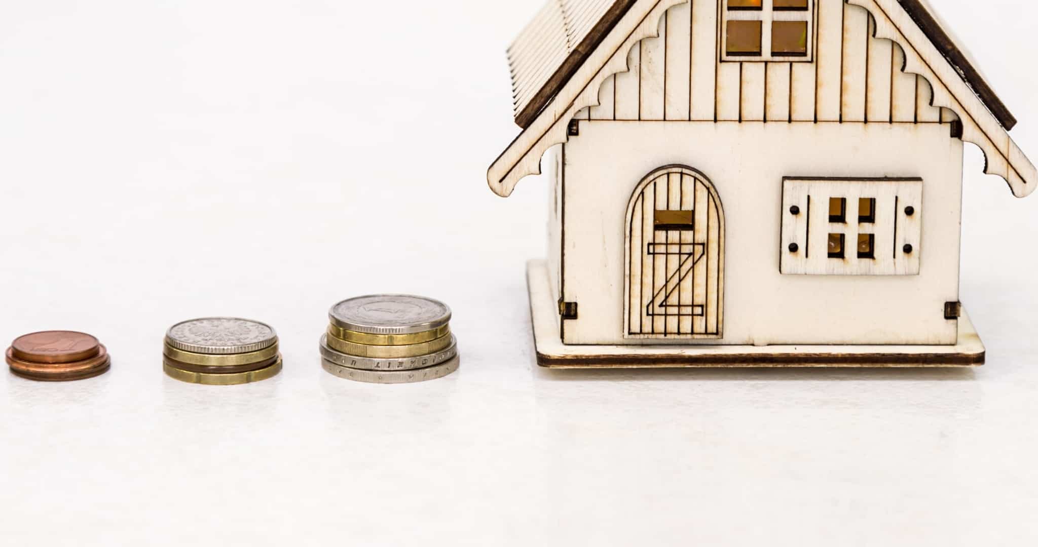 Casa em madeira e molhos de moedas a simbolizar seguro de vida no crédito habitação