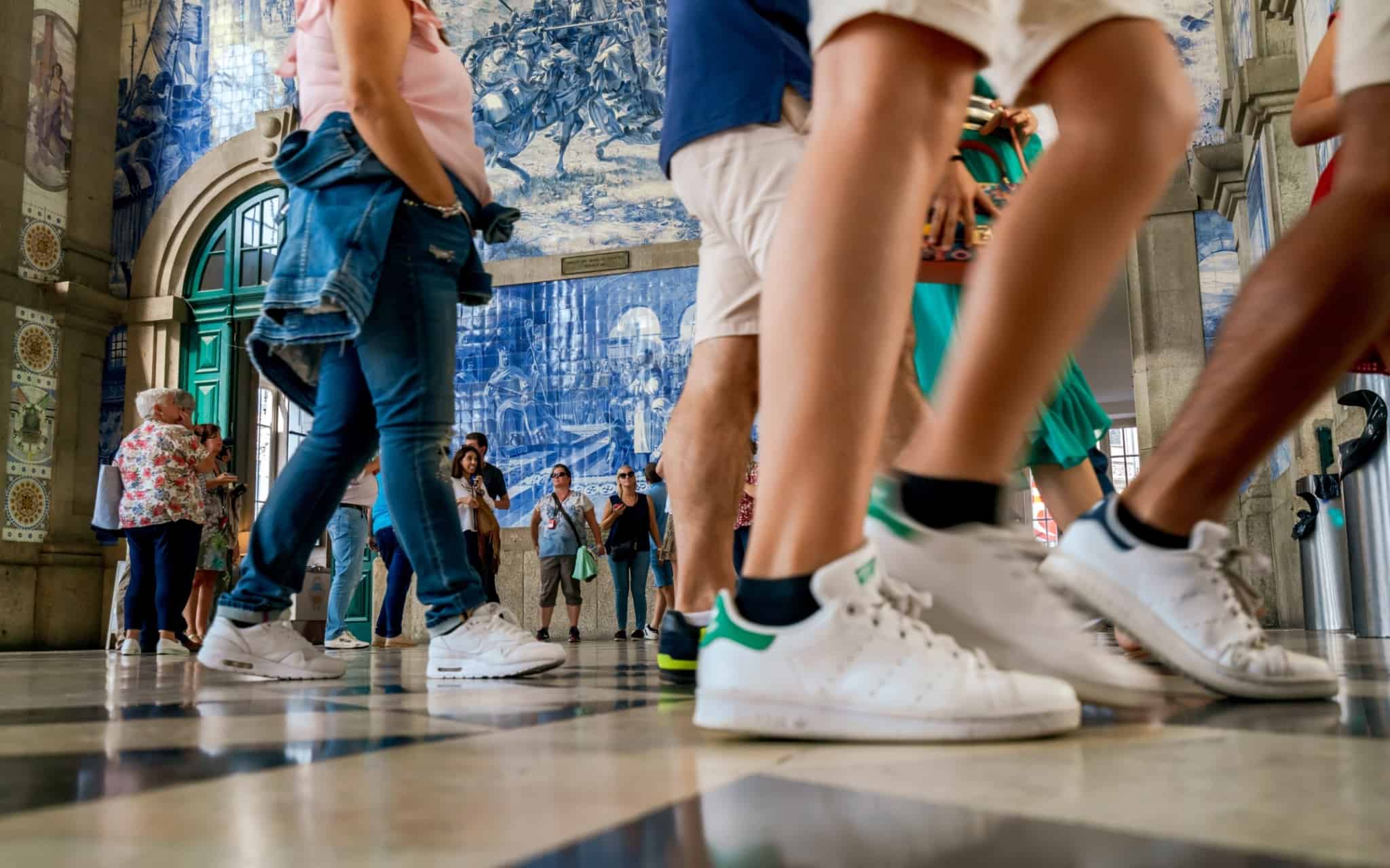 Imagem que ilustra o movimento numa estação - pessoas a andar, só se vê os pés - apoios sociais ias