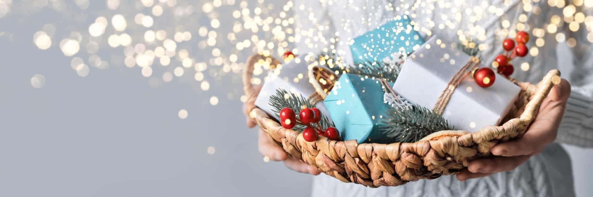jovem mulher segura uma cabaz de Natal, feiro com pequenos embrulhos coloridos, e envoltos em luzes da quadra