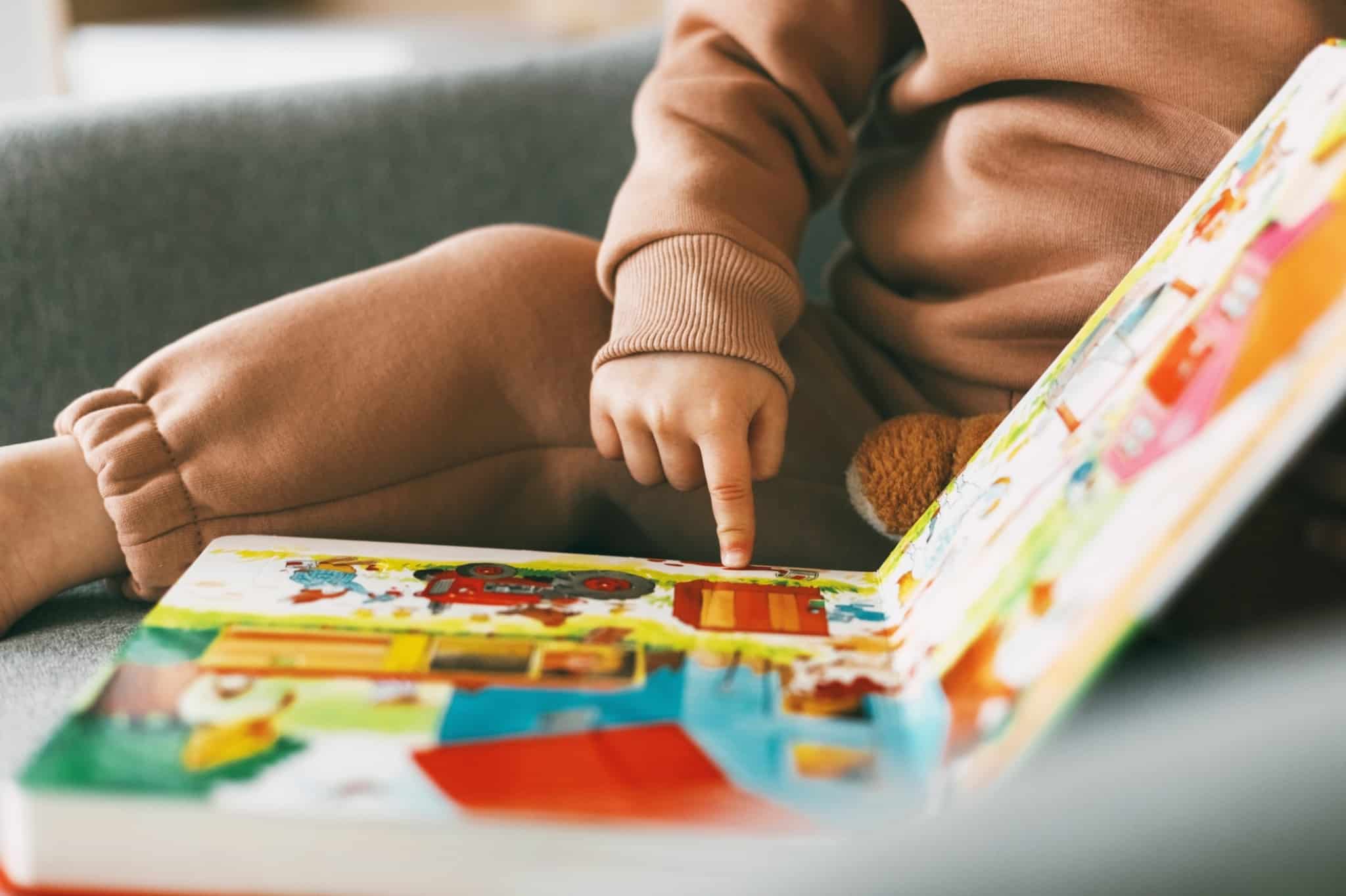 mão de um bebé a mexer num primeiro livro de atividades
