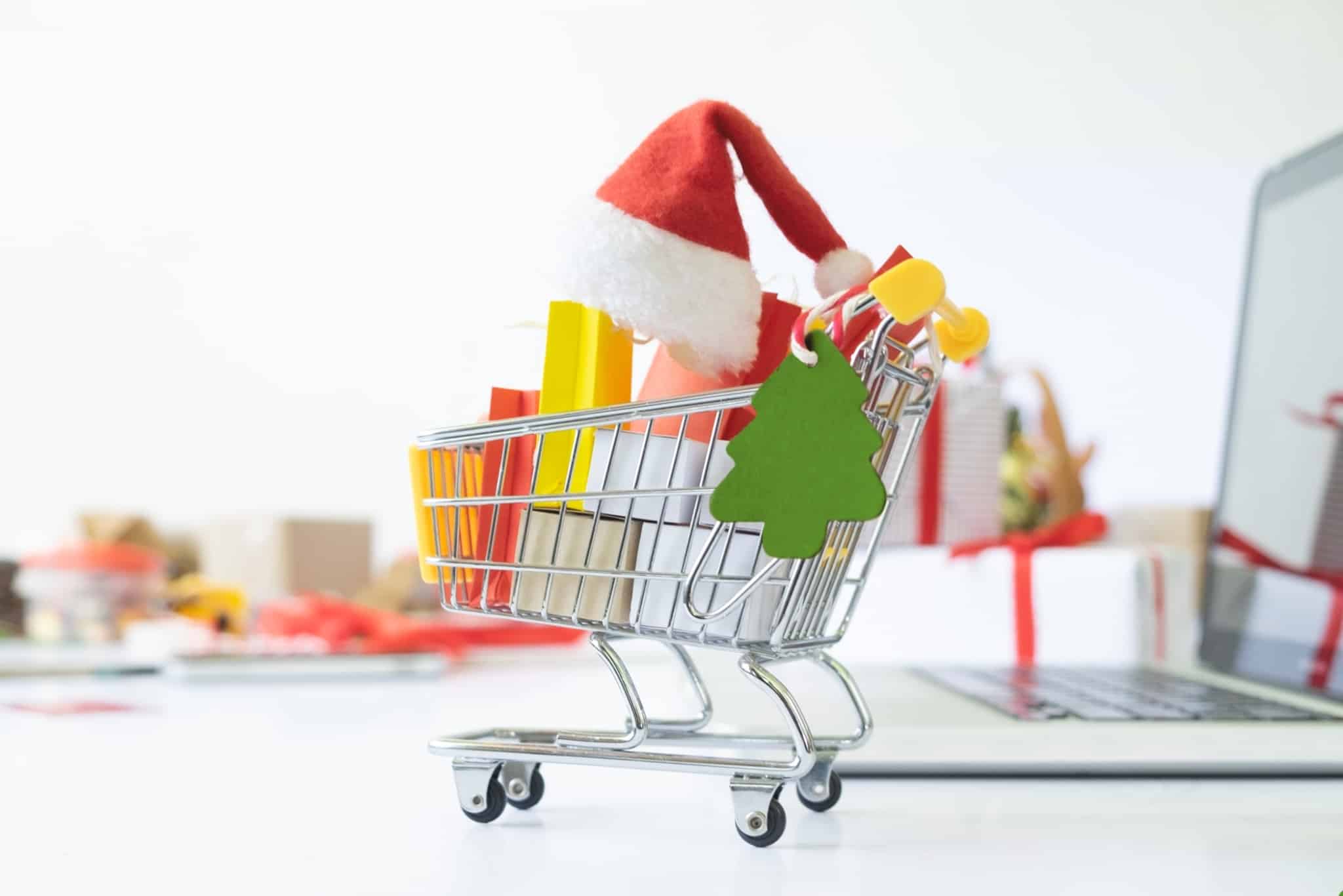 despesas de Natal ilustradas com produção fotográfica que juntou símbolos da época dentro de um carrinho de supermercado miniatura, colocado em cima de um computador portátil e embrulhos de Natal