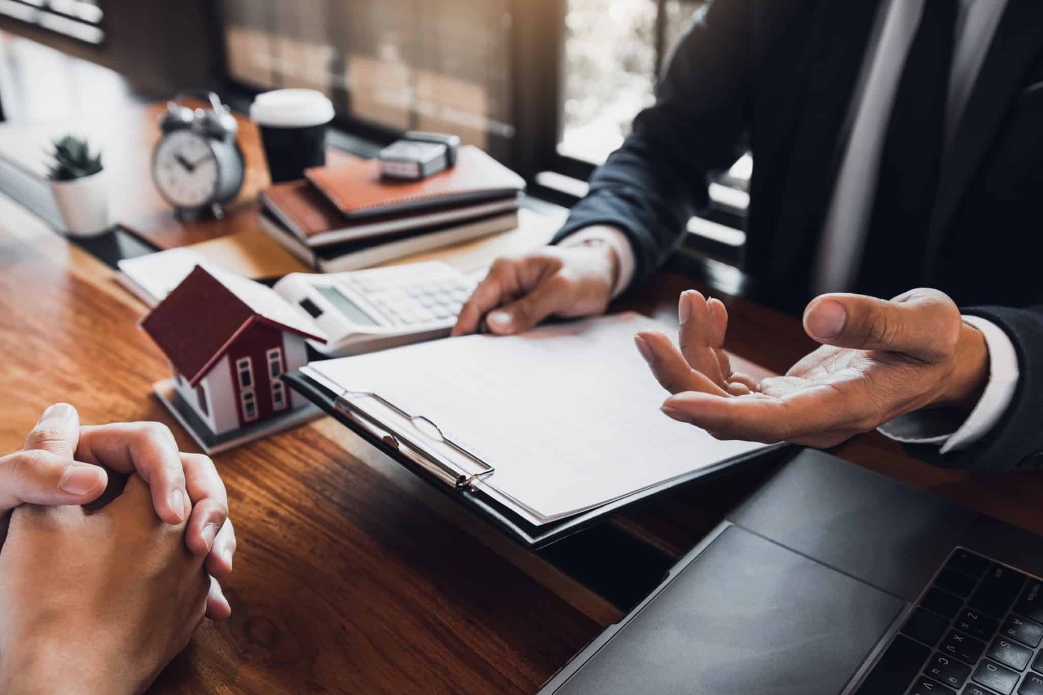 dois homens, numa mesa de escritório, analisam papel para assinar
